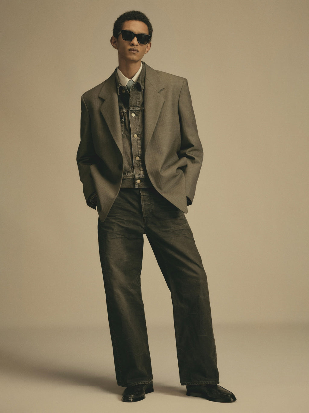 full-length view of male model wearing black washed cotton canvas utility pants with relaxed straight leg and layered blazer and denim jacket