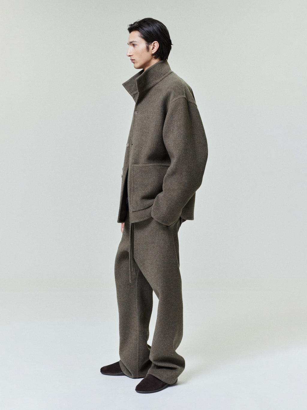 model wearing olive double face wool cashmere flared pants with matching oversized jacket and dark slip-on shoes