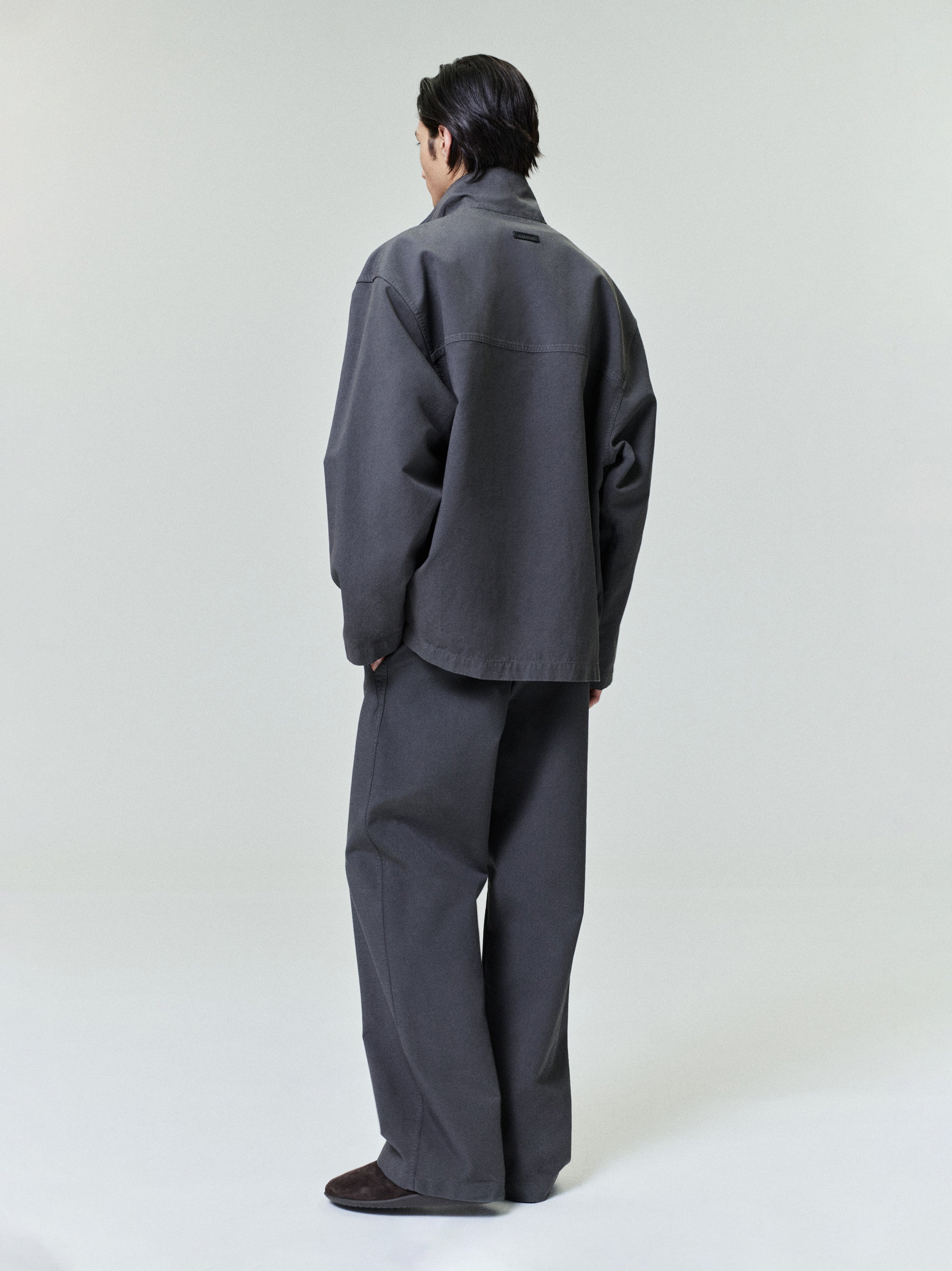male model wearing dark grey garment dyed heavy double weave cotton casual flat front pants and matching jacket