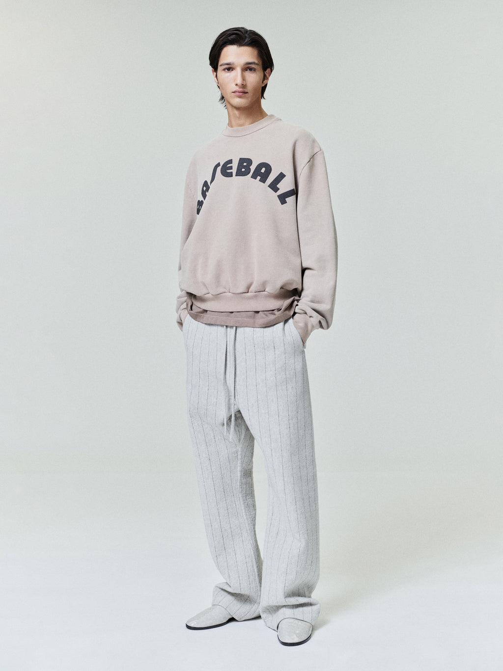 male model wearing light grey pinstriped wool nylon flared pants with elasticated back and satin tape side seam