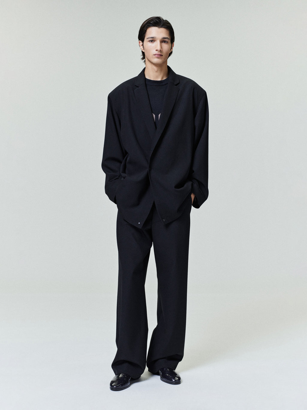 Man wearing a black suit standing against a white background