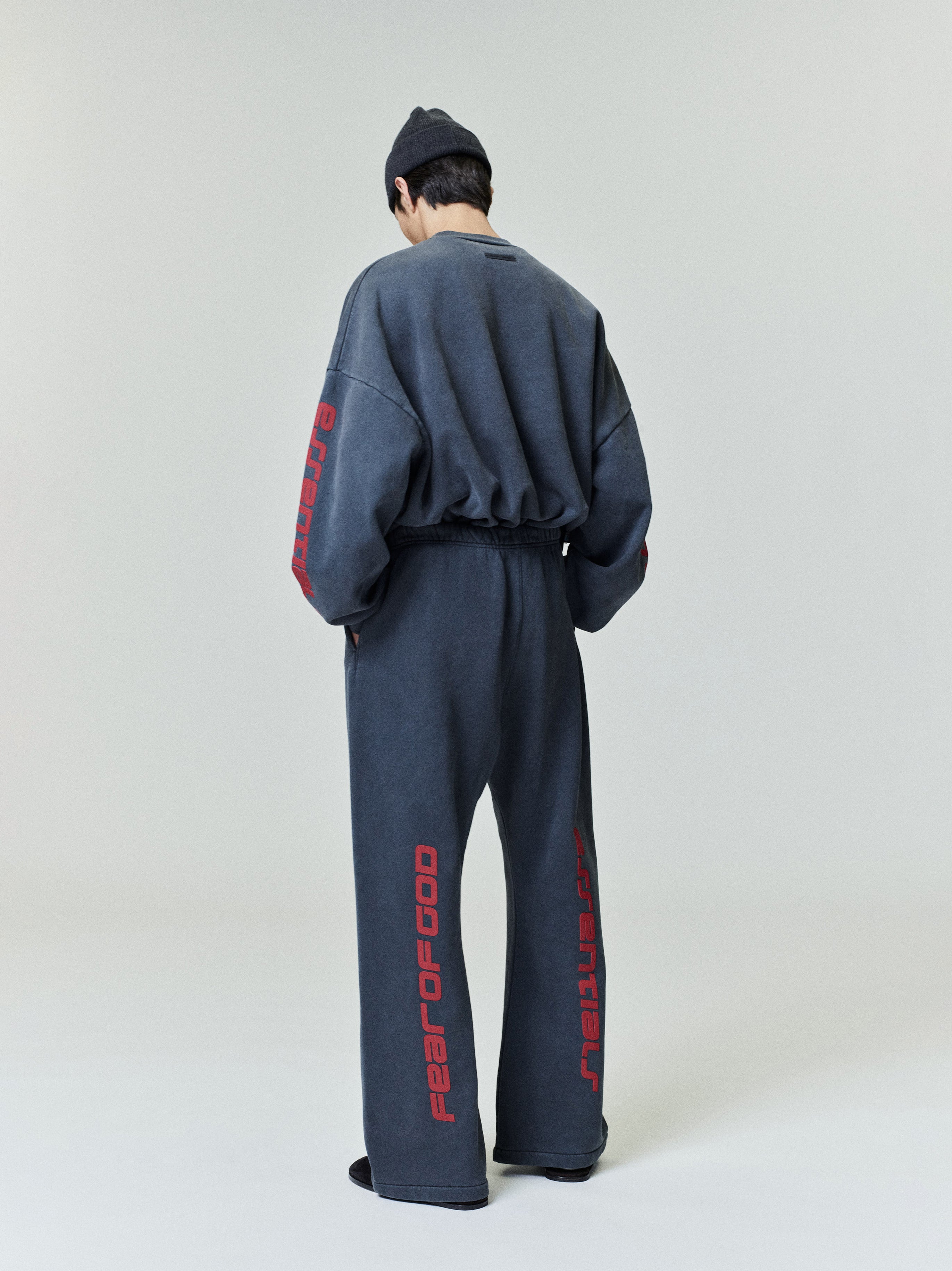Model showcasing back view of slate gray Heavy Fleece Flare Sweatpant with red vertical script on legs and sleeves, gallery 0