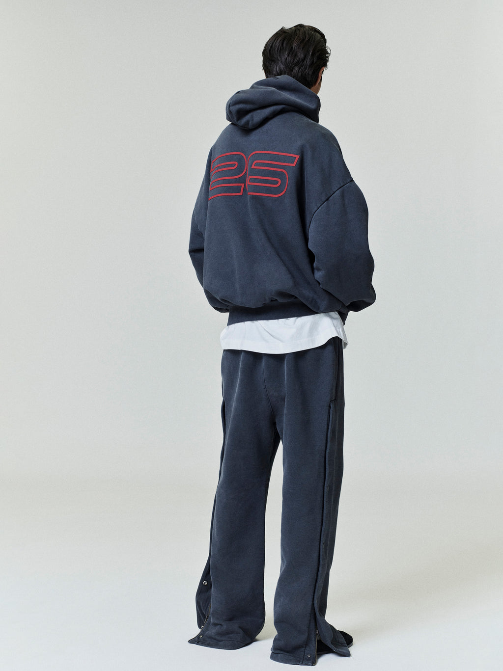 Person wearing a black tracksuit with '25' on the back against a white background