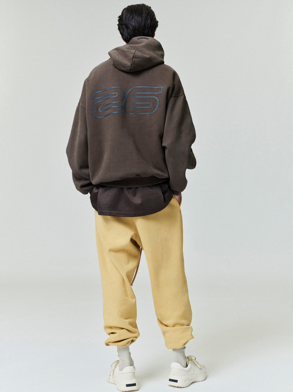 Rear view of model wearing brown Heavy Fleece 90s Hoodie with large outlined number 26 and beige pants 0049_HO25_F_L60_P33_2877.jpg