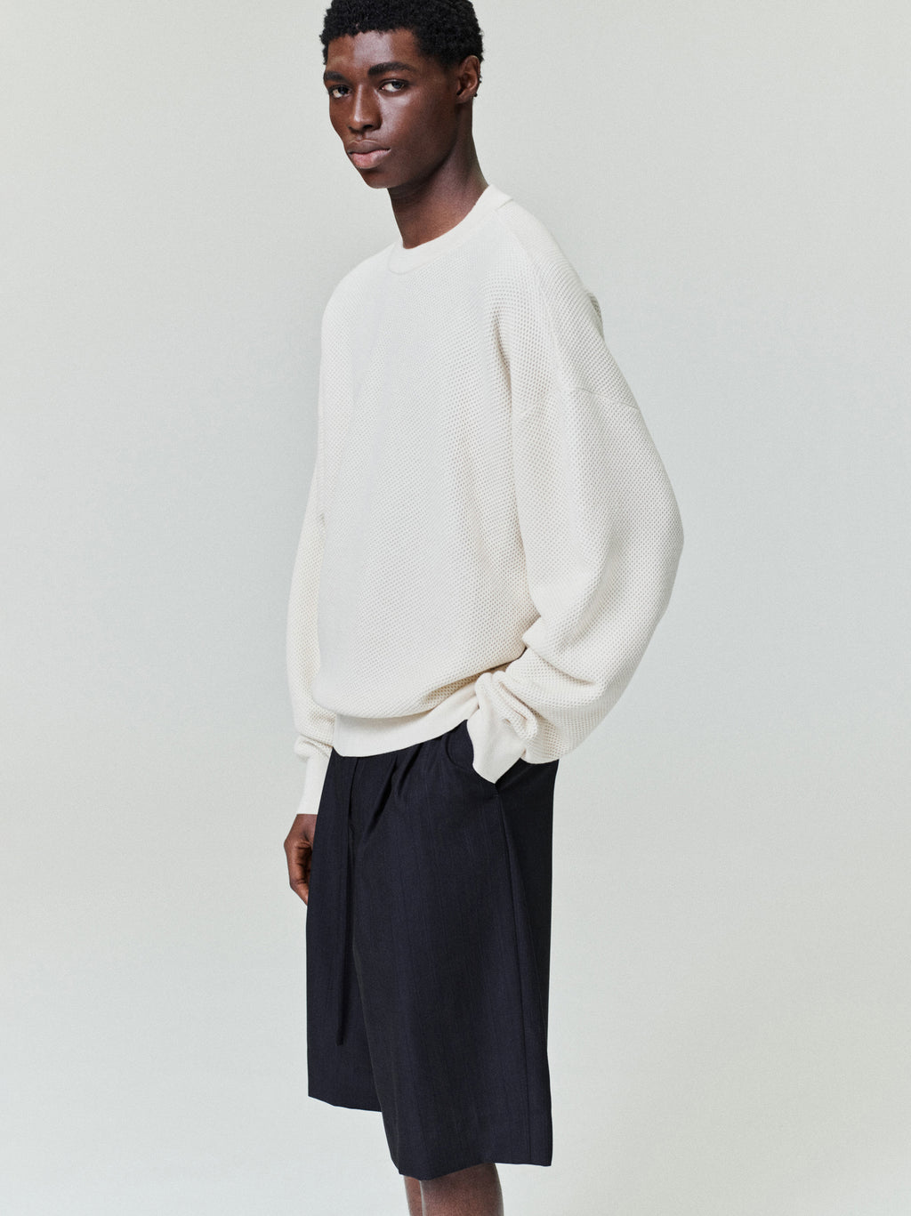 side view of men's off-white double-knit sport mesh wool-cotton crewneck sweater with relaxed fit and long sleeves