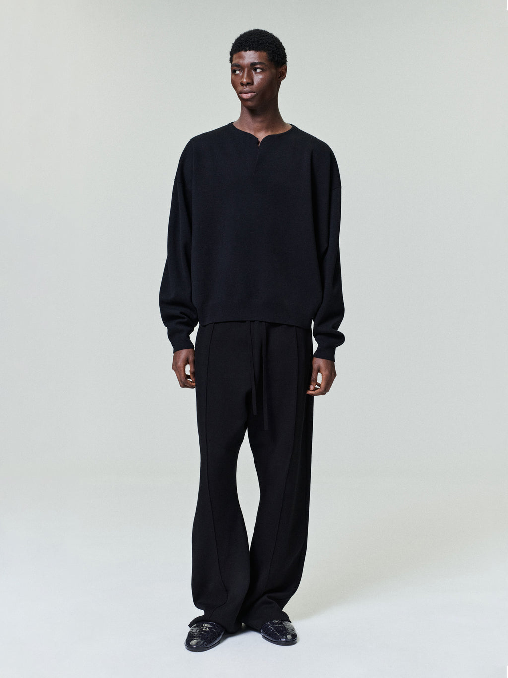 front view of men's black relaxed fit Merino Milano stitch Henley sweater with long sleeves and ribbed cuffs