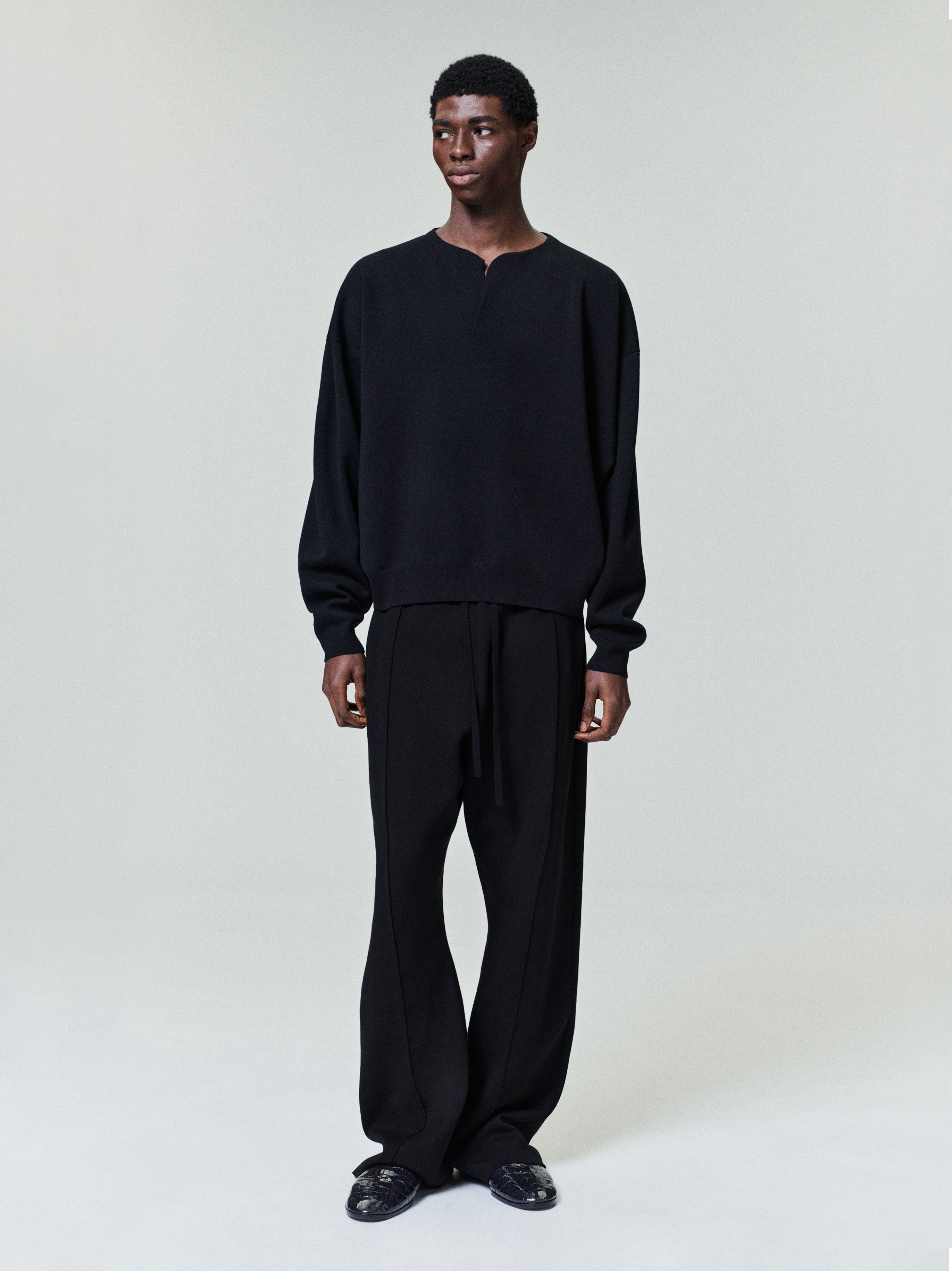 front view of men's black relaxed fit Merino Milano stitch Henley sweater with long sleeves and ribbed cuffs