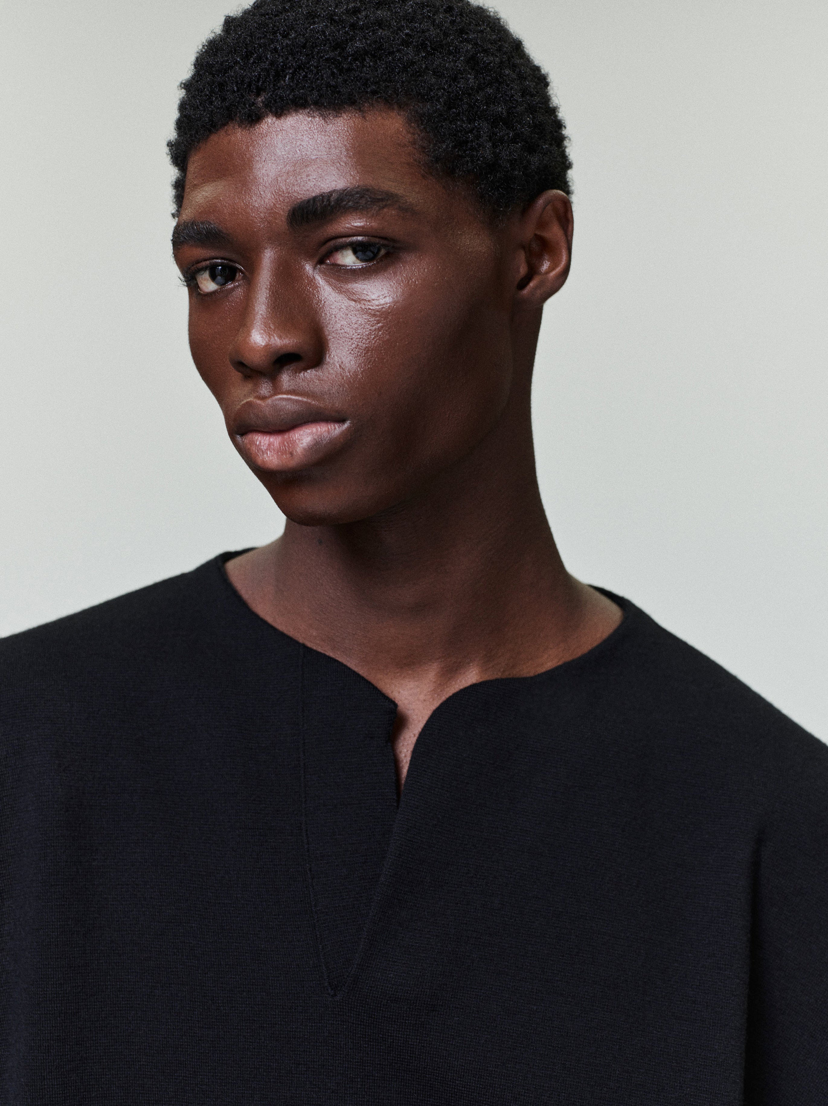 close-up of men's black Merino Milano knit Henley sweater with relaxed fit and subtle V-neck opening