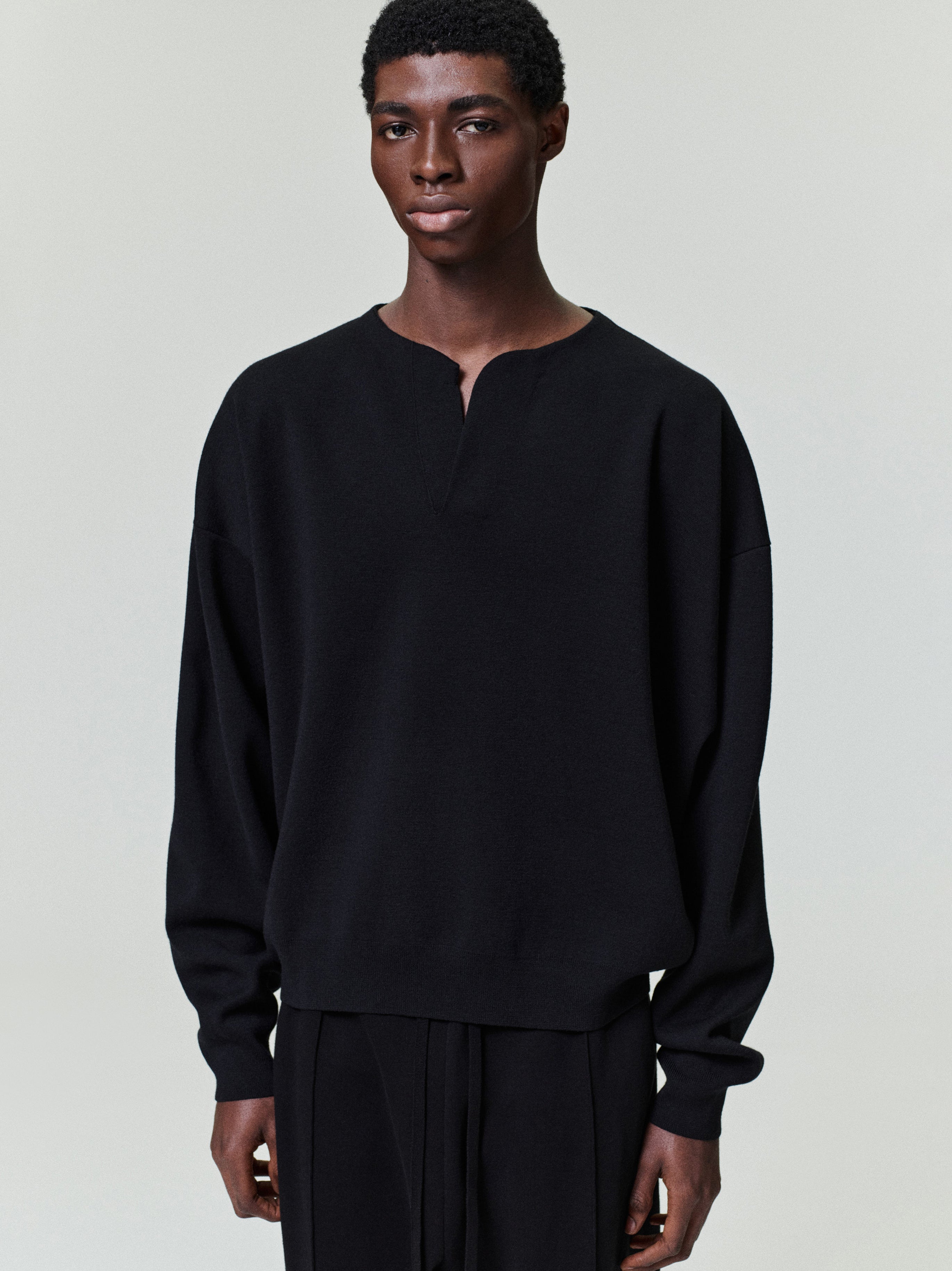 front view of men's black Merino Milano stitch Henley sweater with relaxed fit and long sleeves