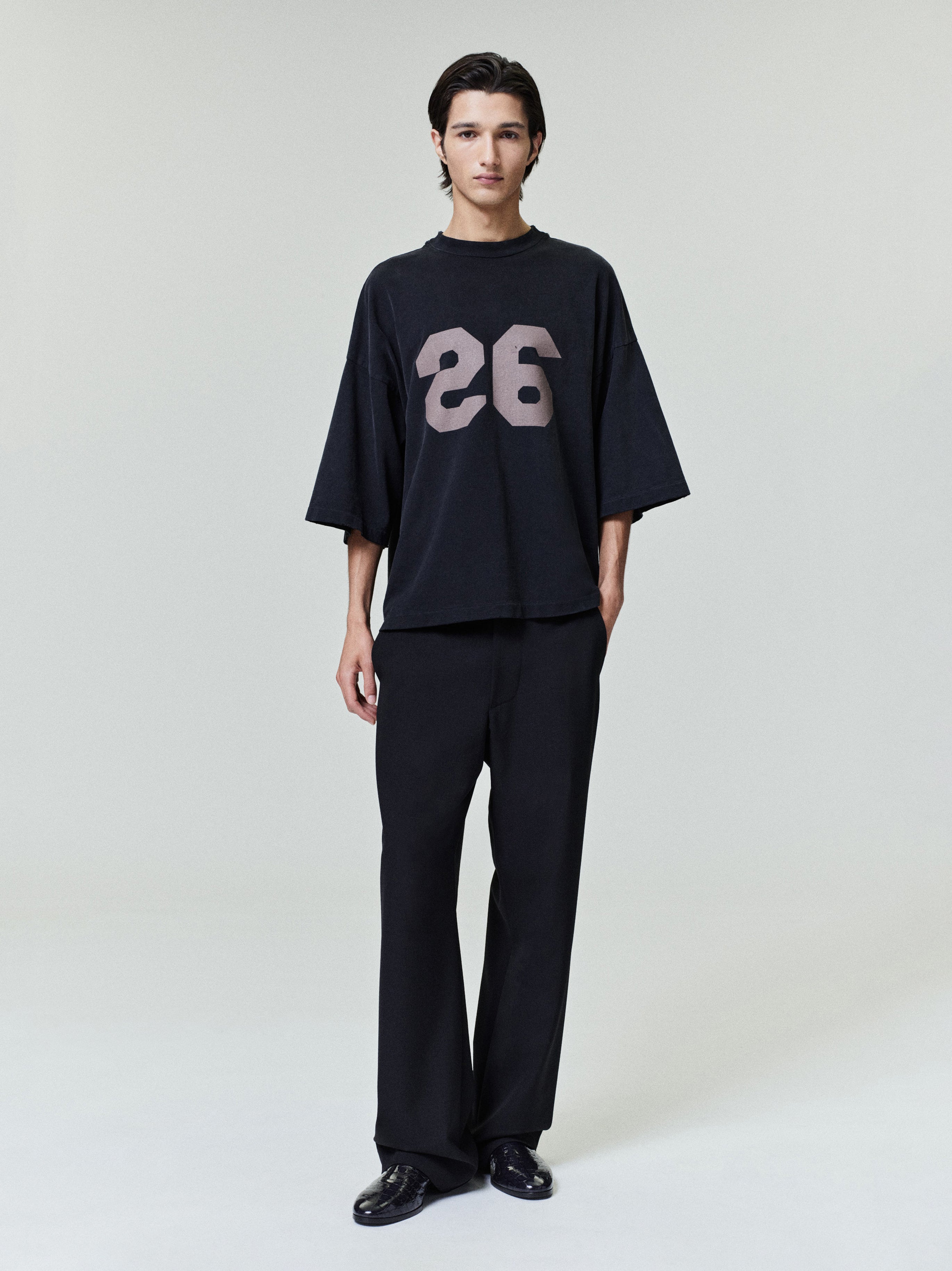 model in oversized black heavyweight cotton tee with large faded number 26 printed on front chest