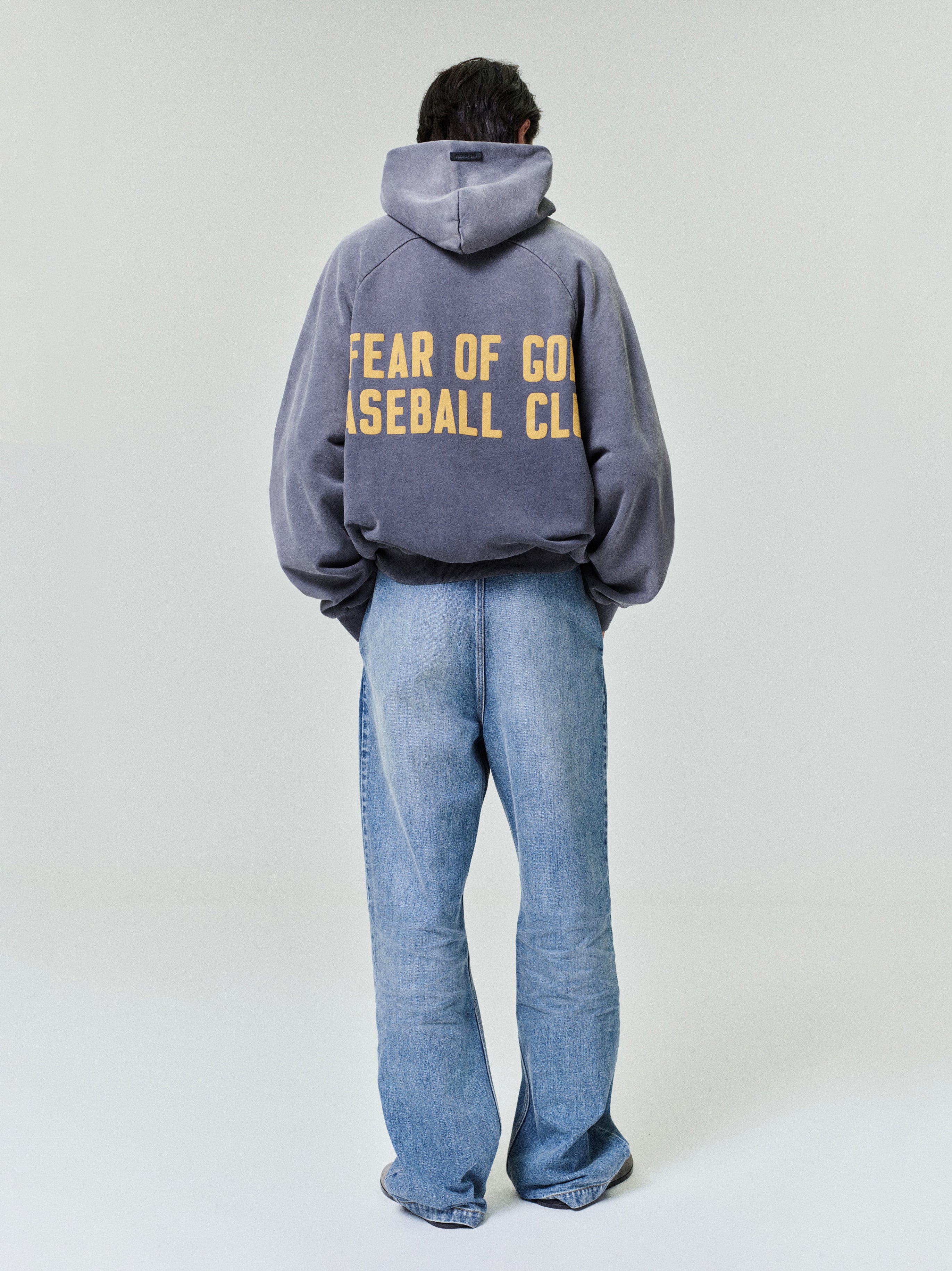 rear view of relaxed fit medium vintage wash denim utility pants paired with oversized hoodie and sneakers