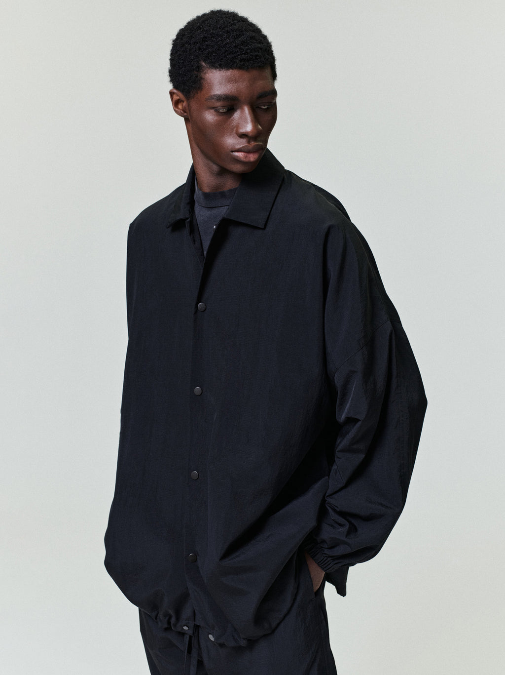 men's black recycled nylon ripstop windbreaker with bonded seams, metal snap buttons, and elastic cuffs and hem
