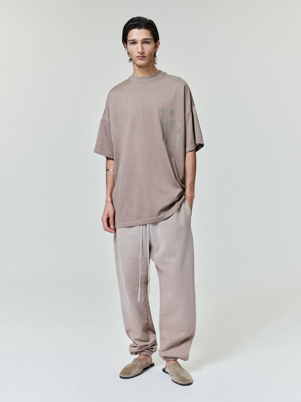 model wearing taupe oversized cotton-rayon tee with subtle printed graphic on chest paired with matching pants