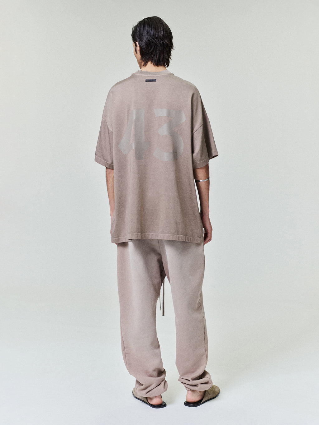 taupe cotton-rayon oversized tee with large subtle "43" hand-printed graphic on back shown on model from behind