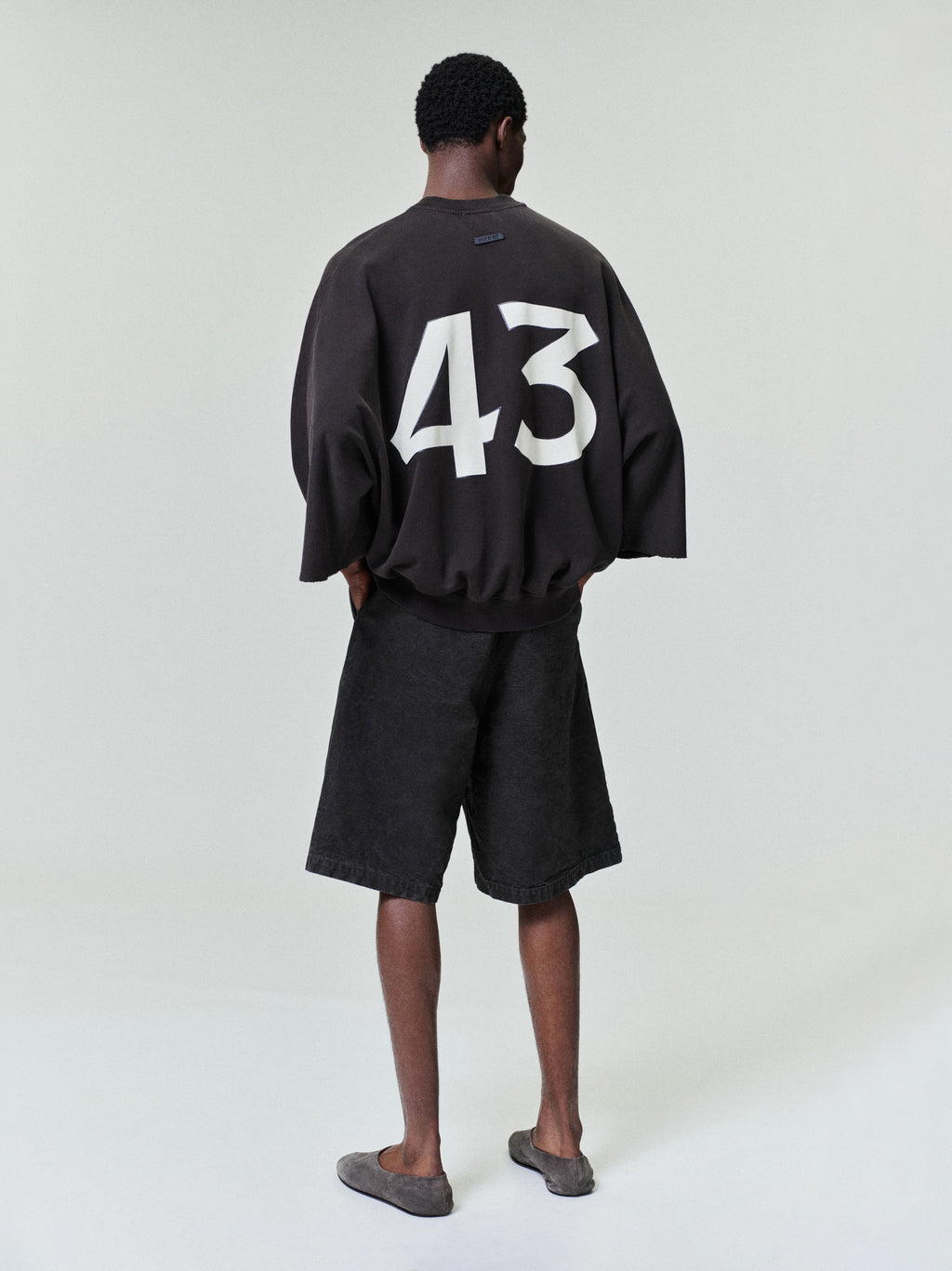 model seen from behind wearing washed black canvas relaxed fit utility shorts with side and back pockets