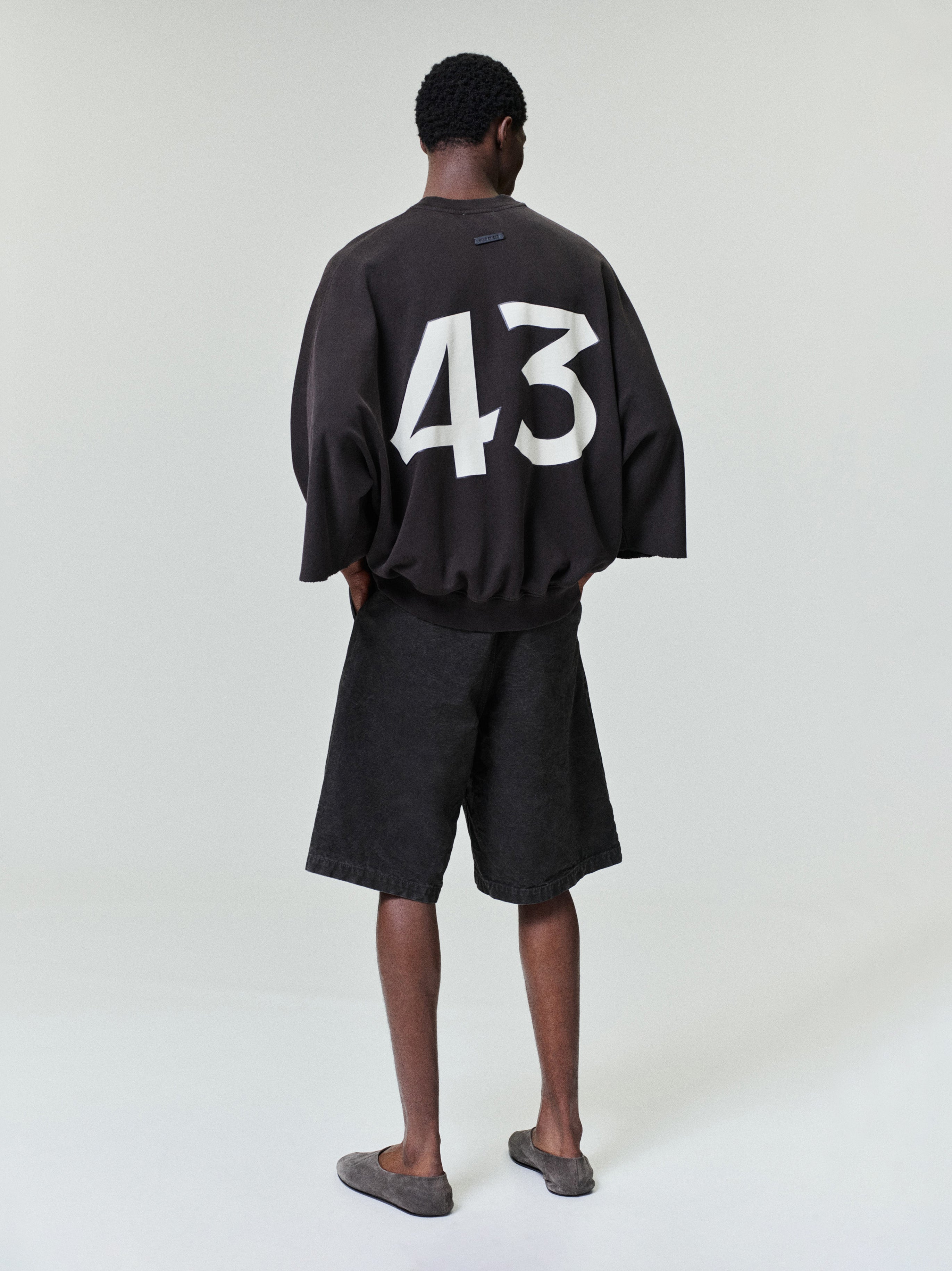 model seen from behind wearing washed black canvas relaxed fit utility shorts with side and back pockets