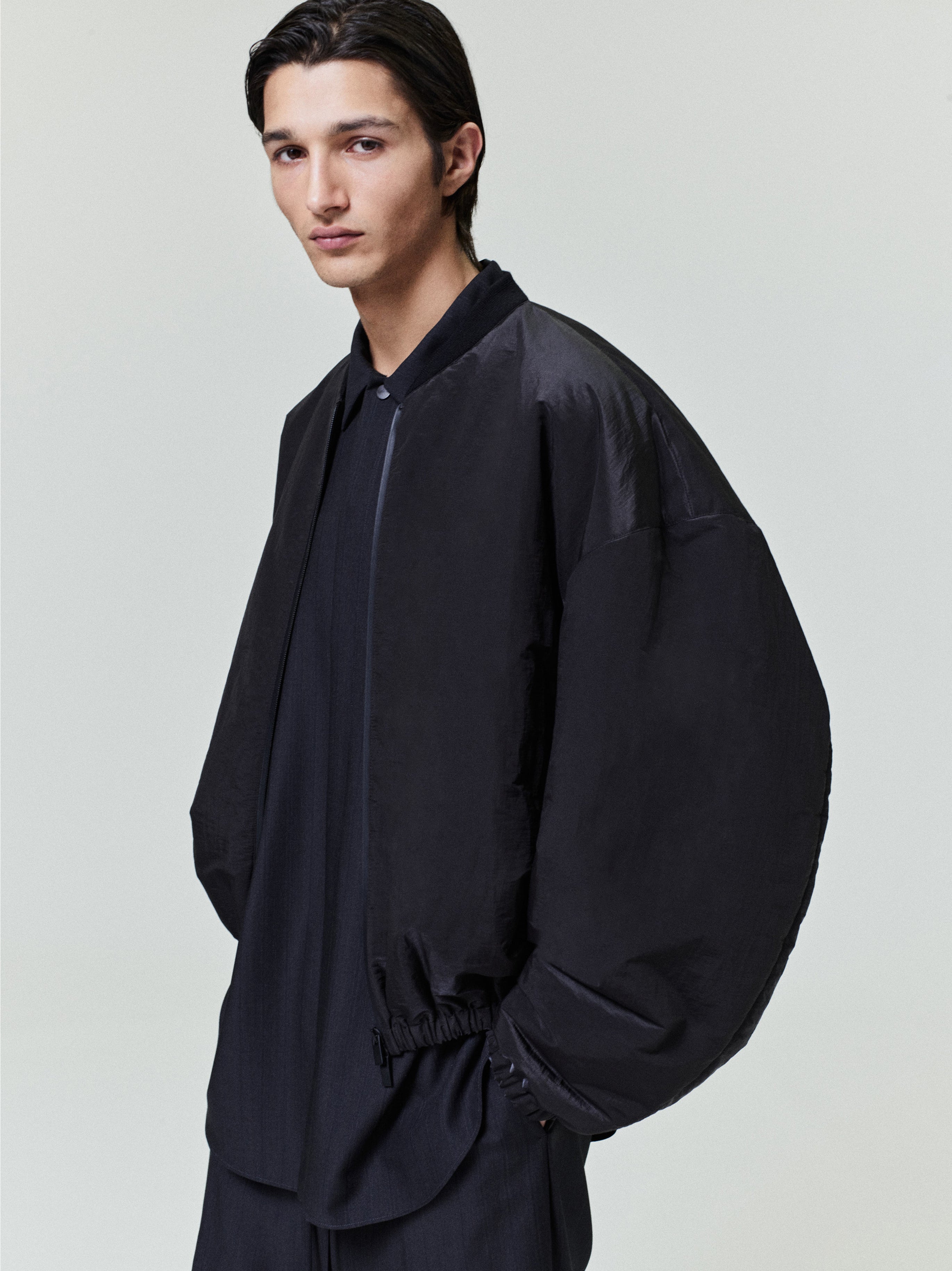 man modeling black lightweight nylon taffeta padded bomber jacket with knit collar and elasticated cuffs