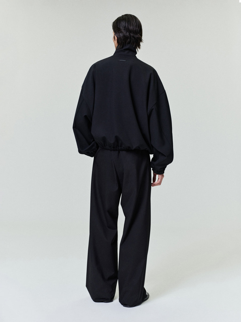 male model wearing black wide-leg ripstop virgin wool pants with elastic waistband seen from back