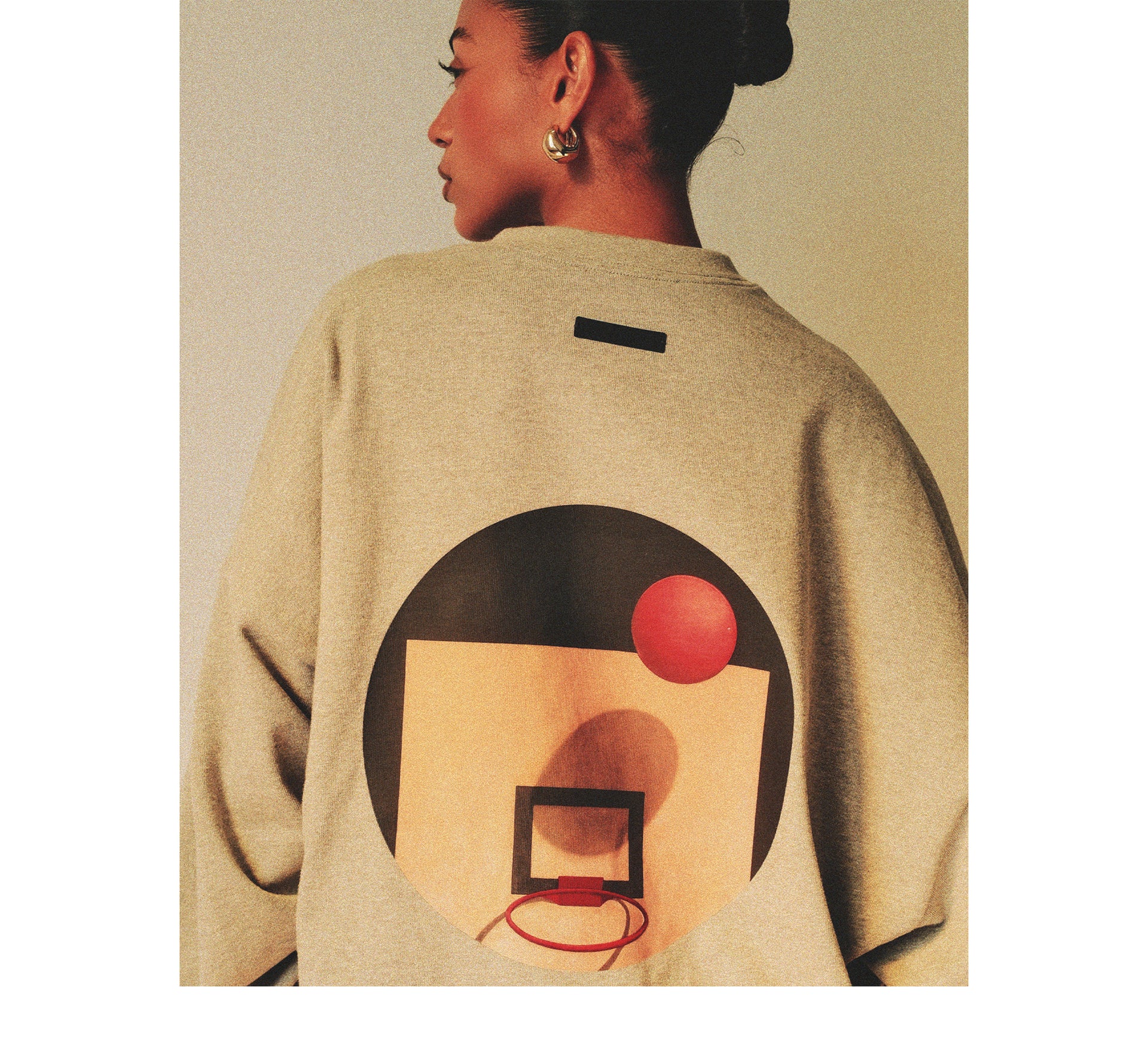 Beige sweater with a basketball design on the back, worn by a person.