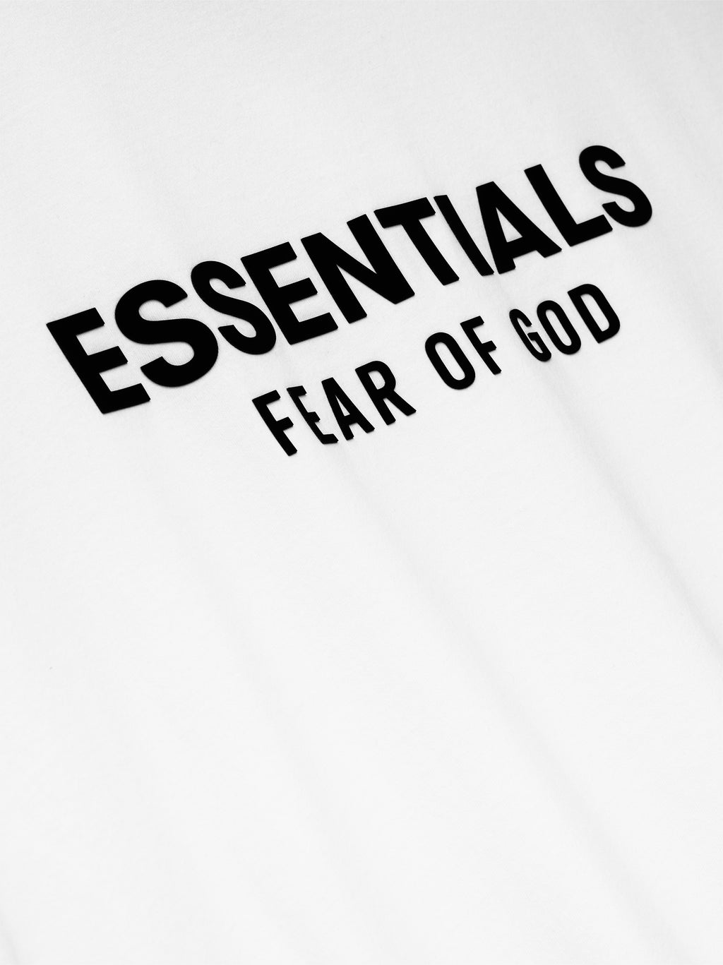 Black ‘ESSENTIALS FEAR OF GOD’ logo on the back of a white shirt.