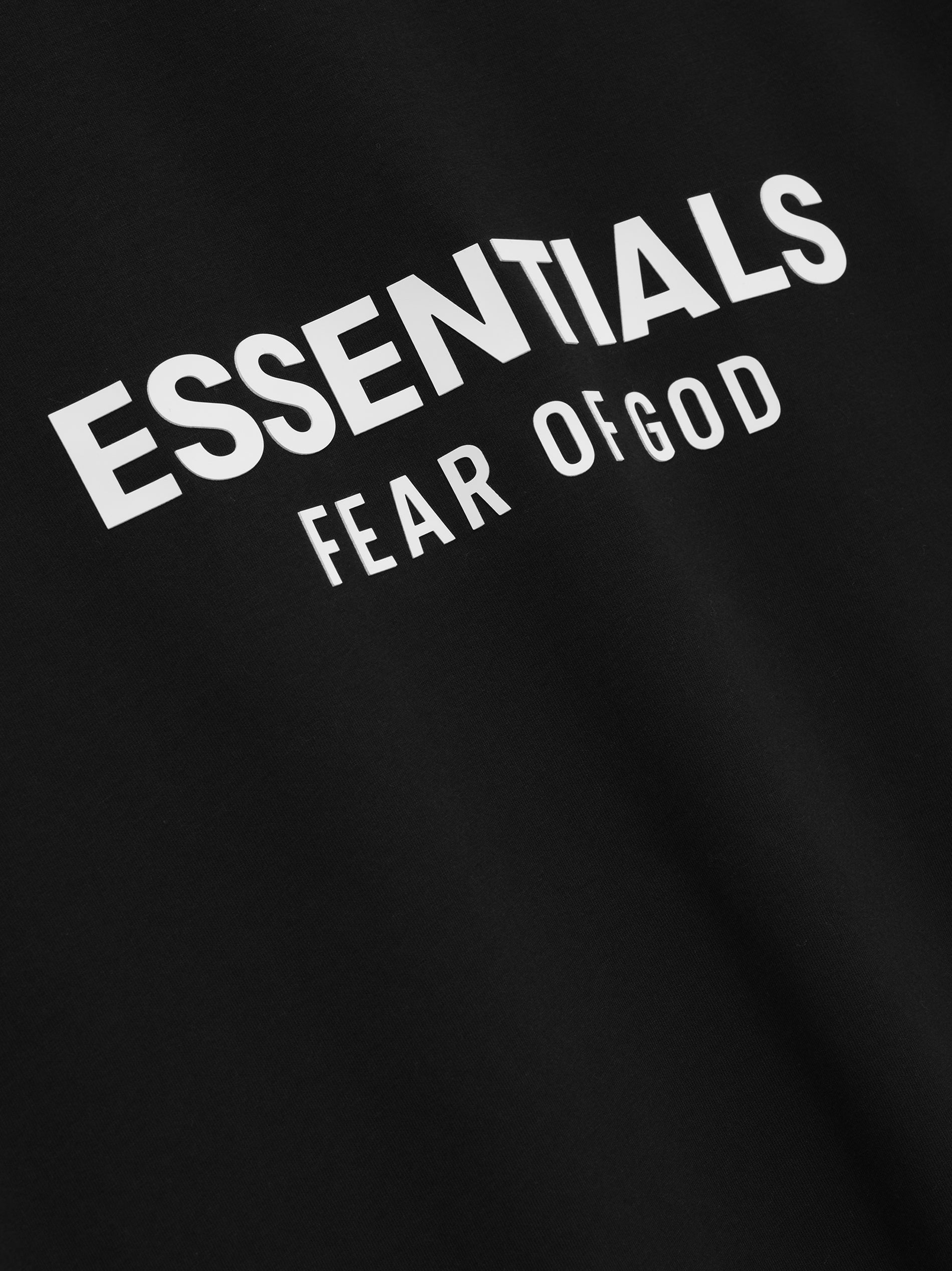 Close-up of jet black Classic Long Sleeve Tee with angled white ESSENTIALS Fear of God logo on chest, gallery image 0