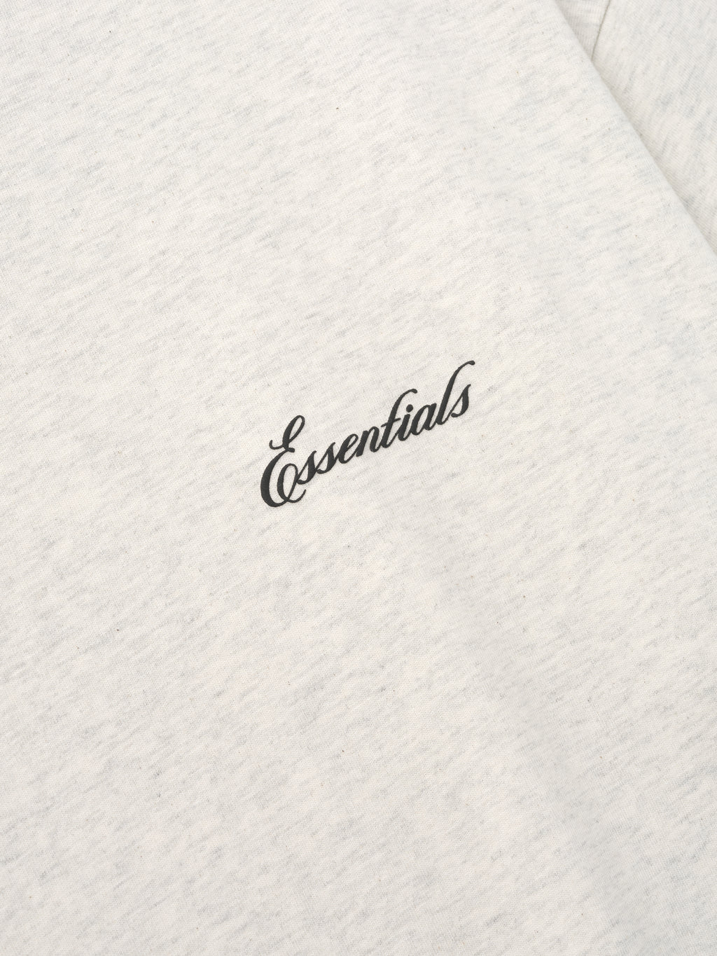 Close up of a white t-shirt with essentials script logo on a white background