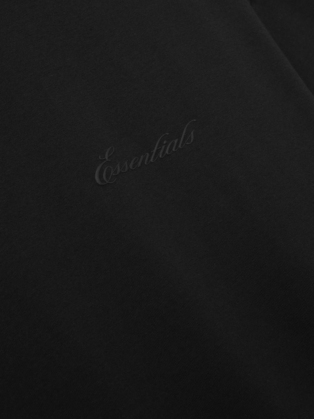 Black tee with 'Essentials' embroidery on a black background