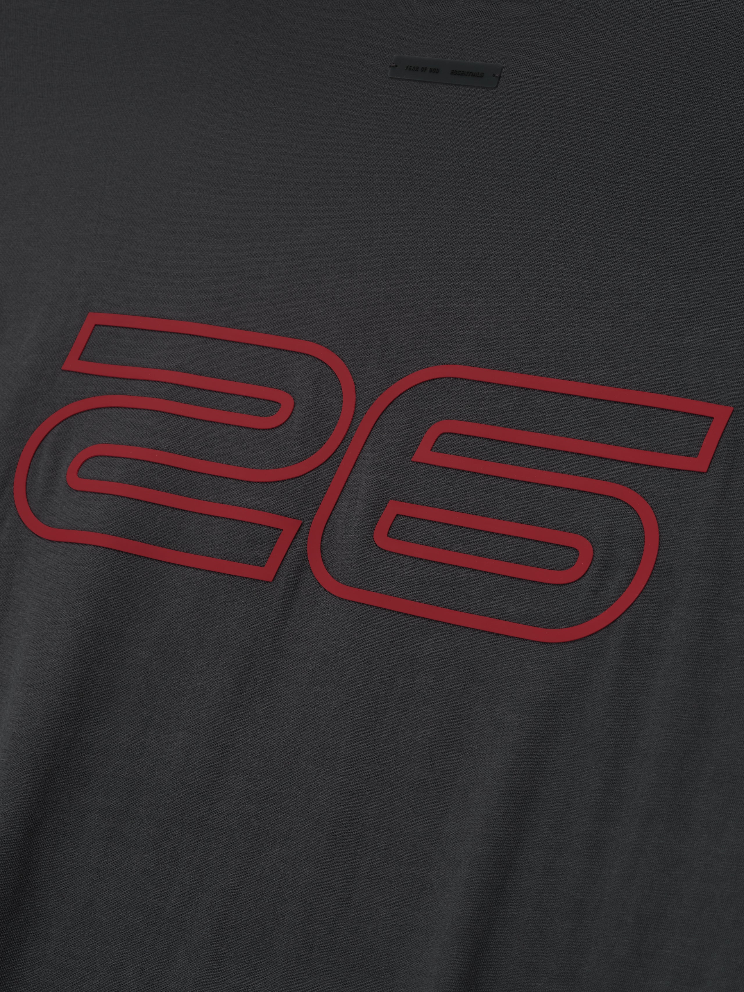 Close-up of iron grey Fear of God Essentials 90s Tee showing bold red numeric 26 print on soft fabric