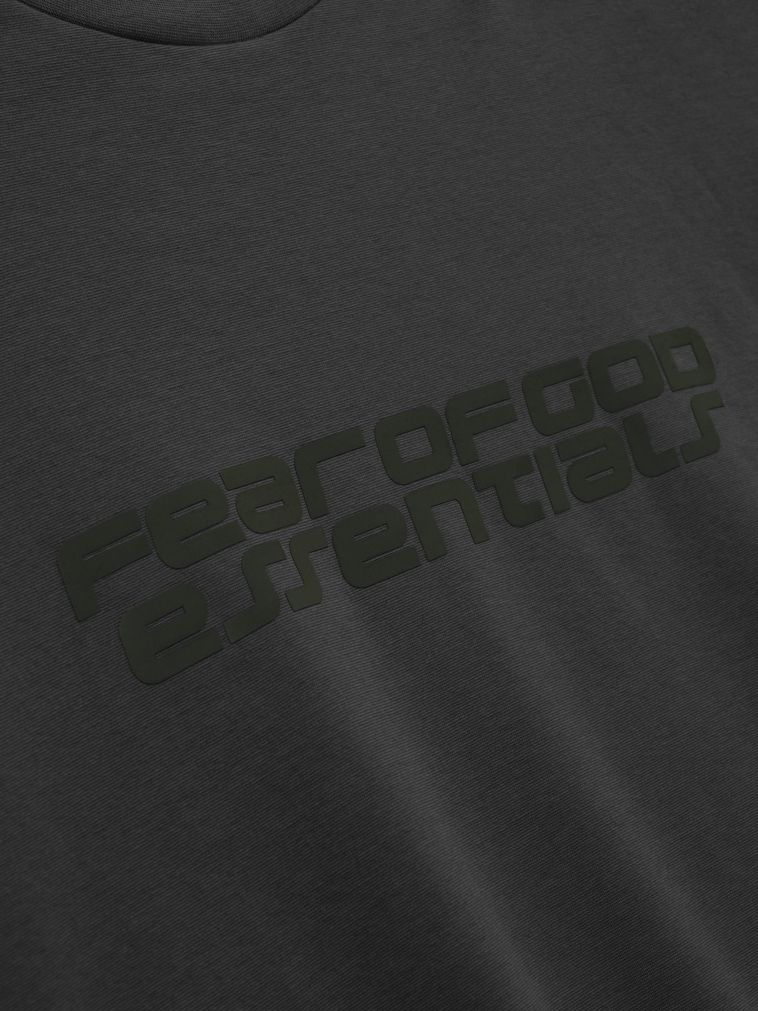Close-up of iron grey Ponte 90s Tee featuring subtle embossed Fear of God Essentials logo on smooth soft fabric