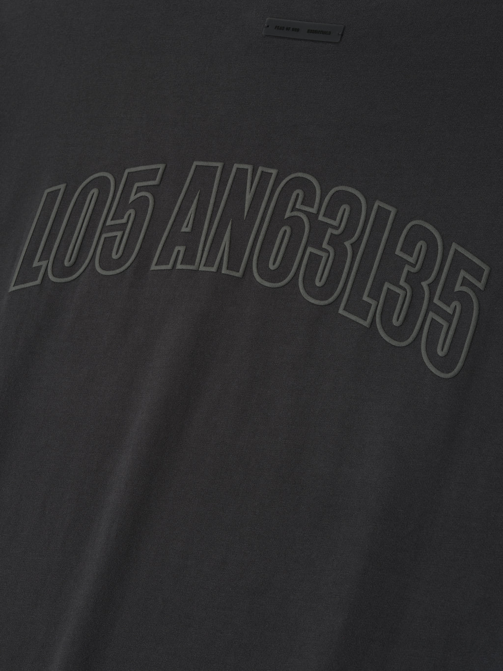 Close-up of vintage black Los Angeles 90s Tee featuring embossed mixed numeric and letter print across soft fabric surface