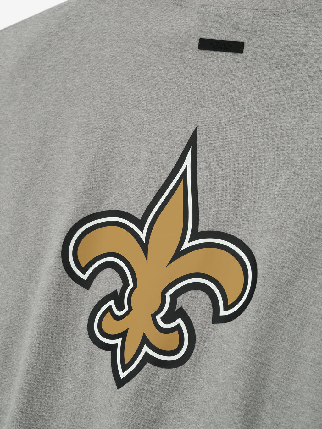 Close-up of concrete heather Saints 90s 3/4 Sleeve Football Tee showing large gold fleur-de-lis logo on back center