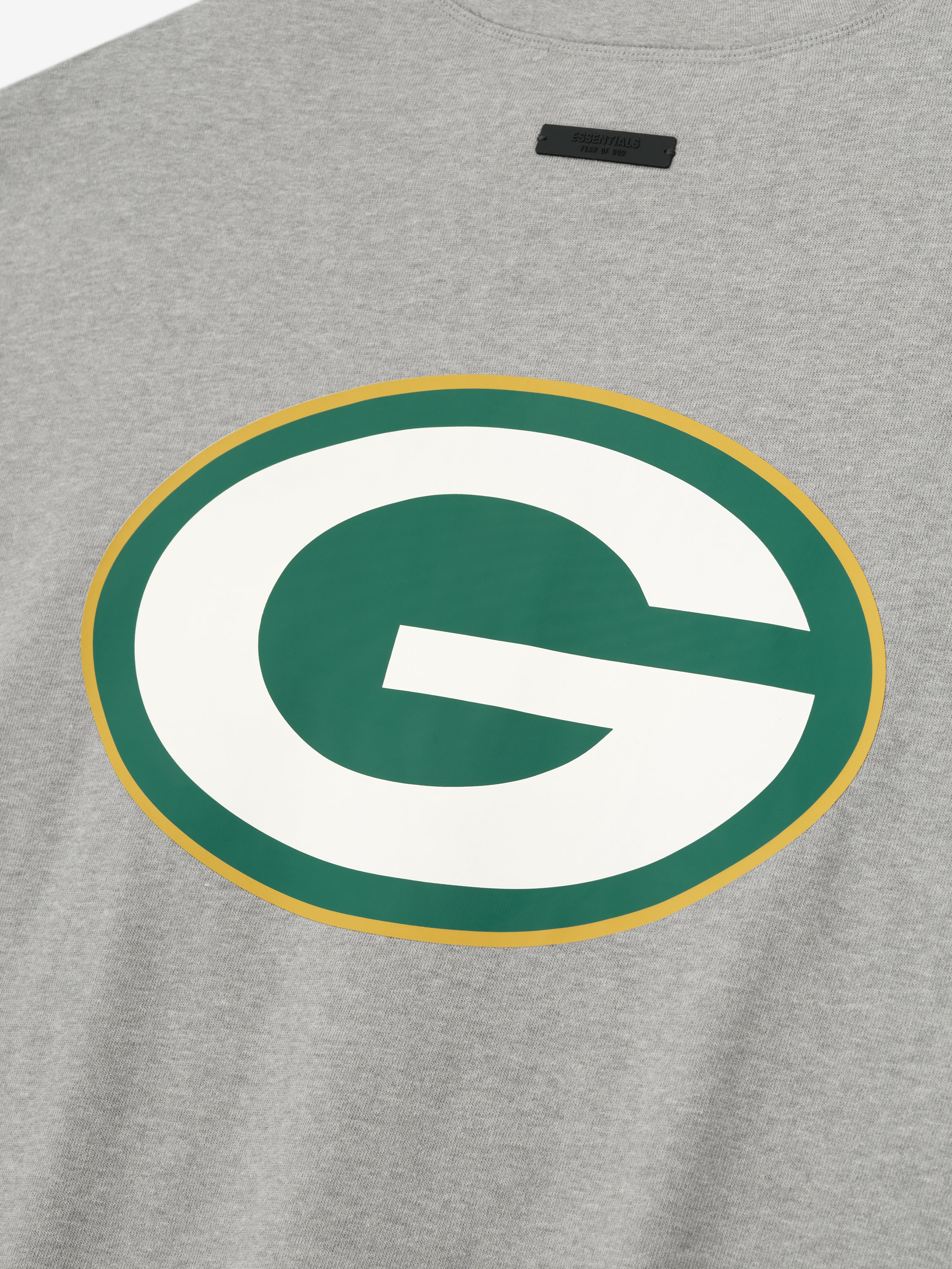 Close-up of concrete heather Packers 90s 3/4 Sleeve Football Tee showing large green and white G logo with gold outline centered