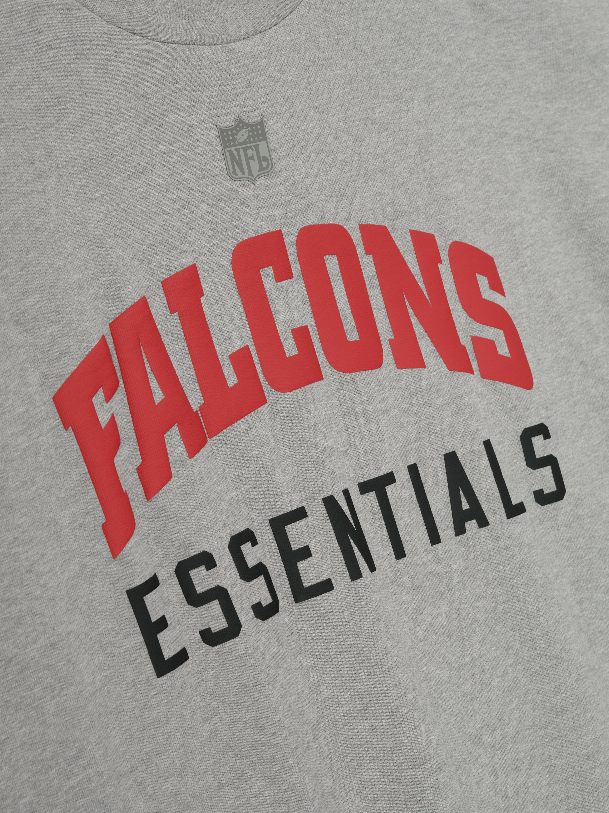 Concrete heather Falcons 90s 3/4 Sleeve Football Tee close-up showing red Falcons and black Essentials lettering on chest