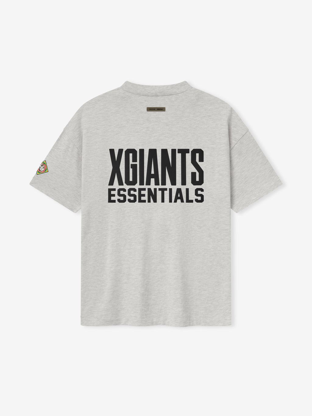 light gray cotton tee with bold black "XGIANTS ESSENTIALS" text on back and multicolored patch on left sleeve