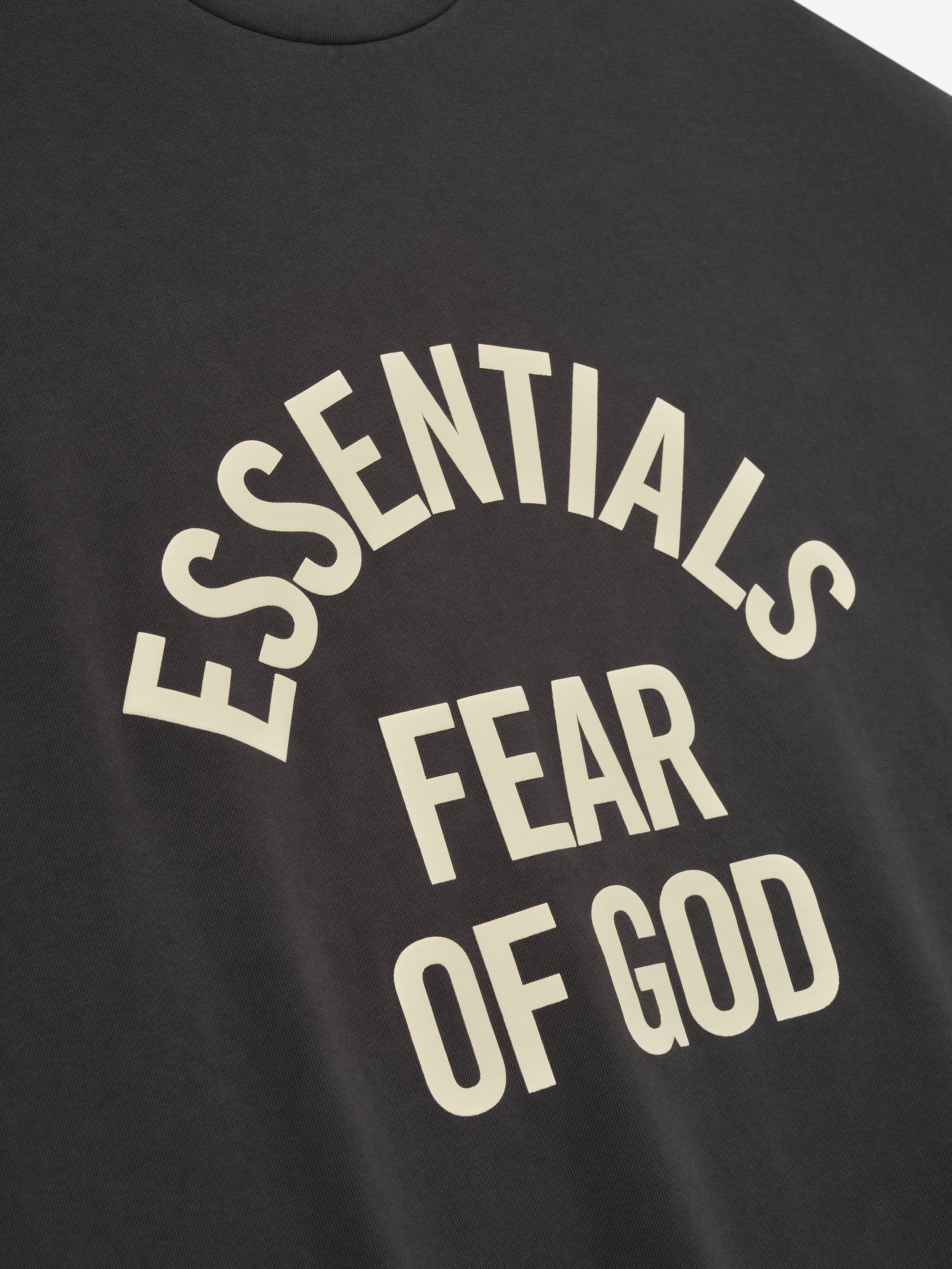 Black t-shirt with 'ESSENTIALS FEAR OF GOD' text in beige.