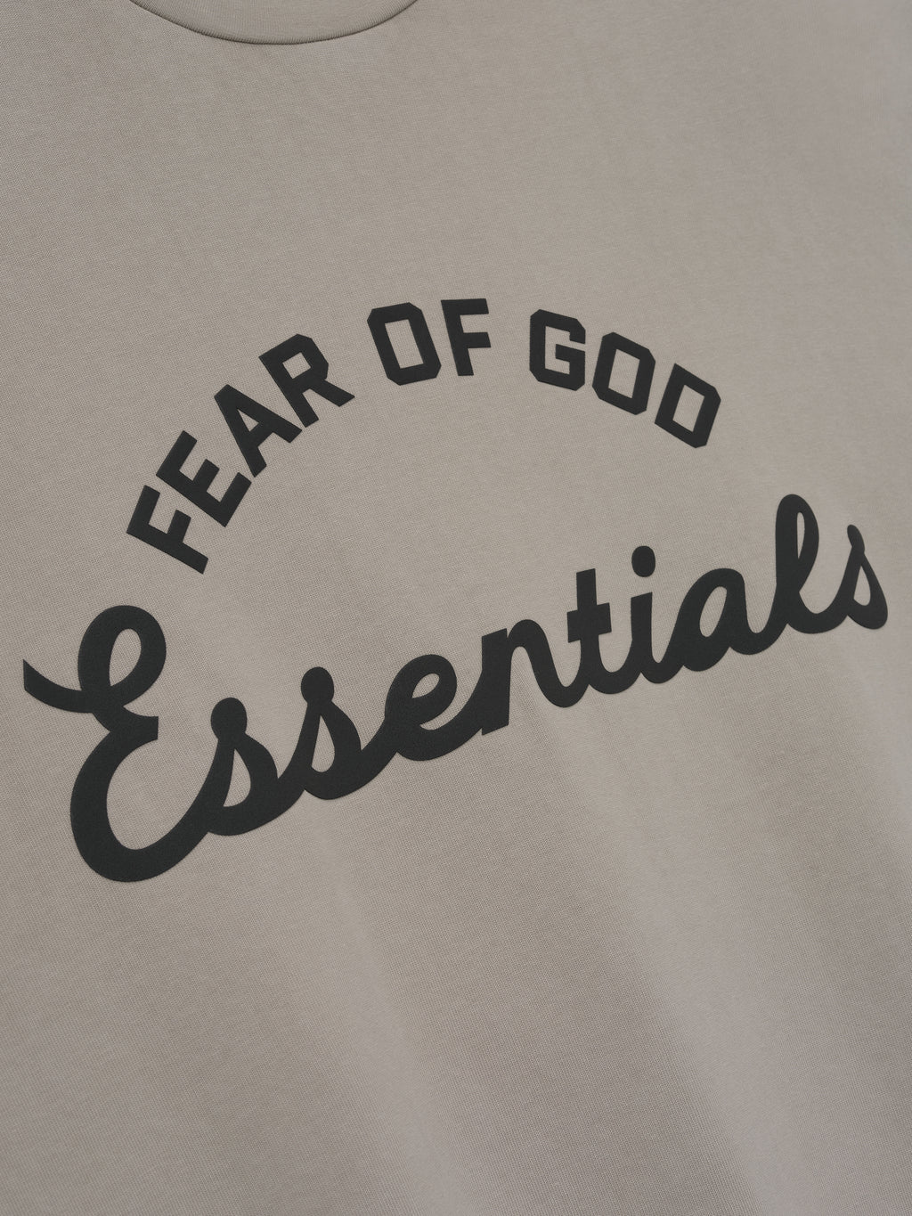 close-up of beige cotton tee with curved Fear of God Essentials logo in bold black print on front
