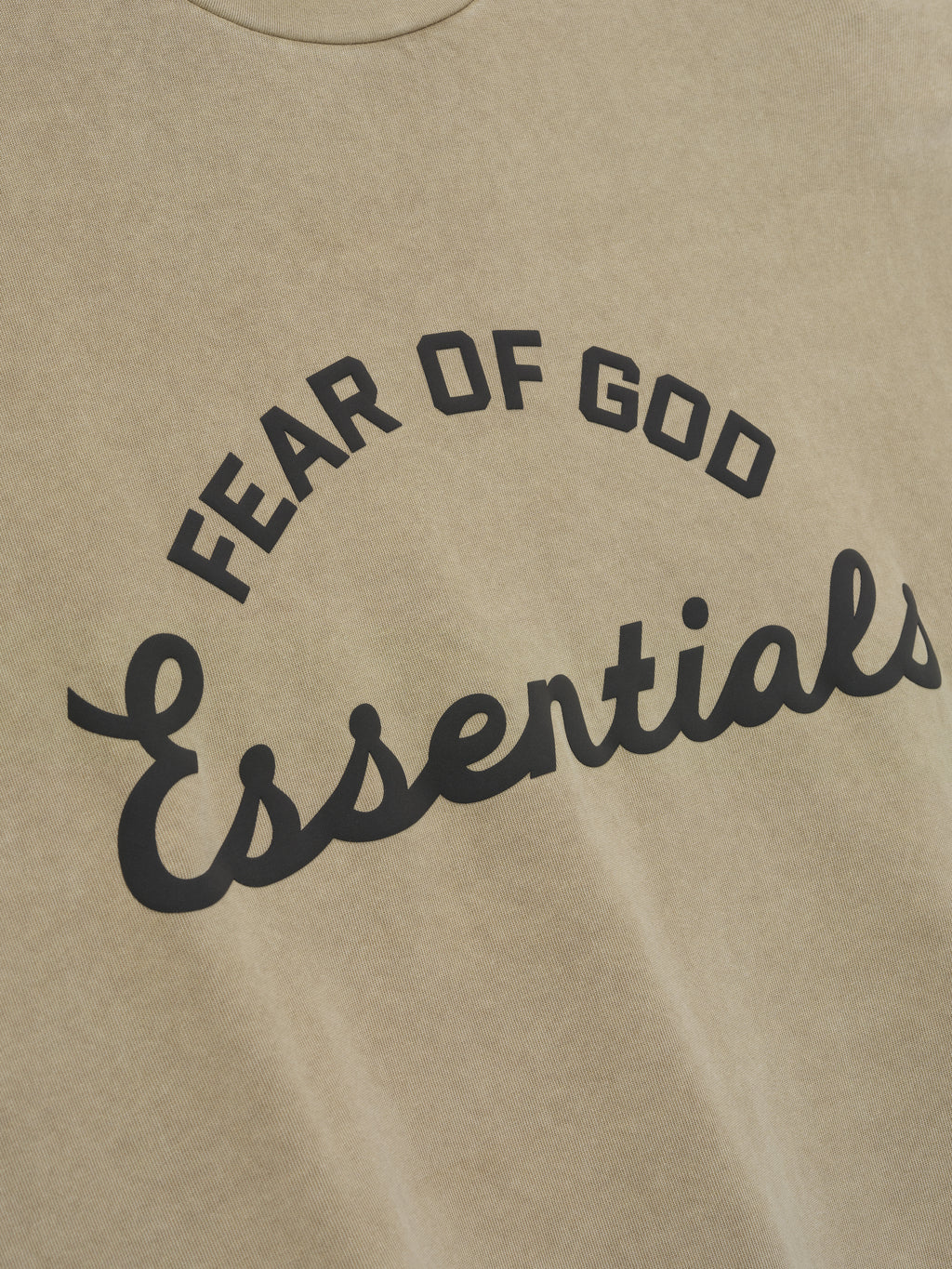 close-up of pigment-dyed vintage beige cotton tee with arched Fear of God Essentials logo in contrasting black print