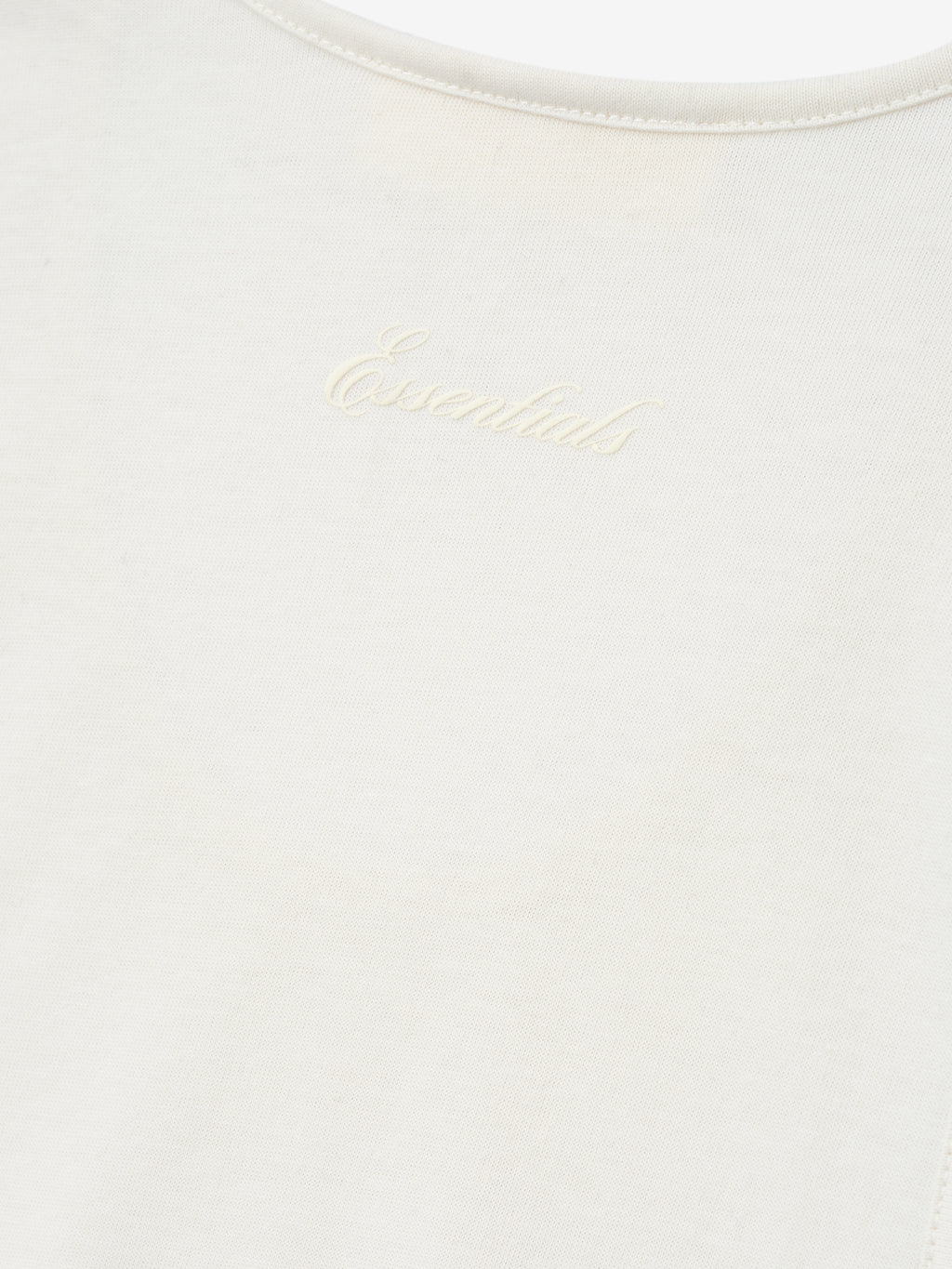 Close-up of a white shirt with 'Essential' script logo
