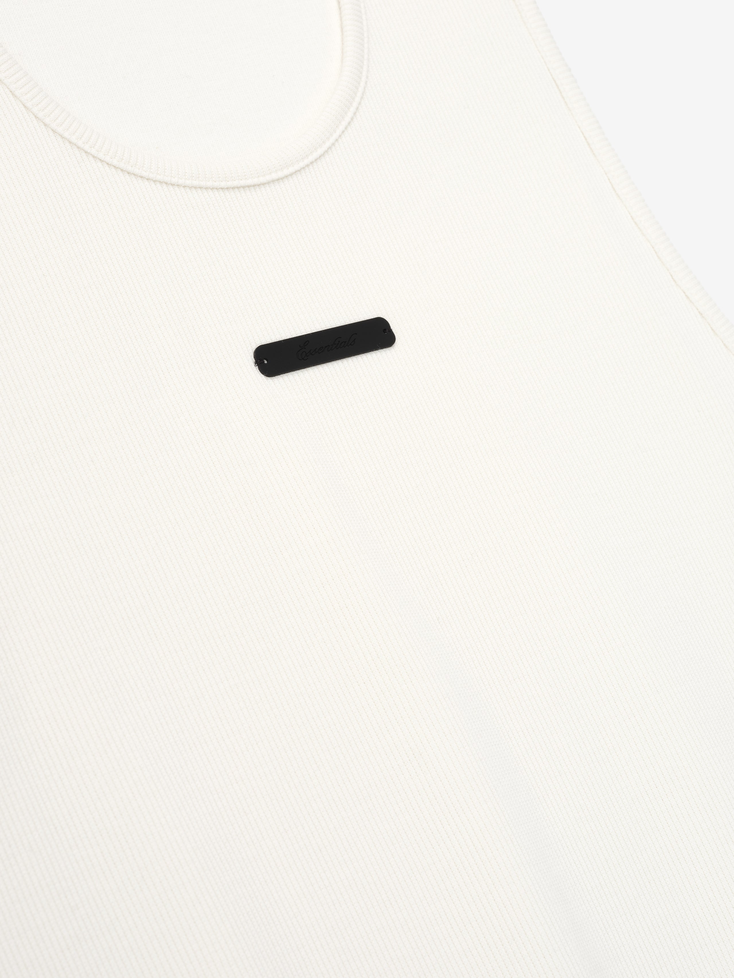 close-up of off-white ribbed cotton spandex tank top with minimalist Essentials signature LA logo on chest