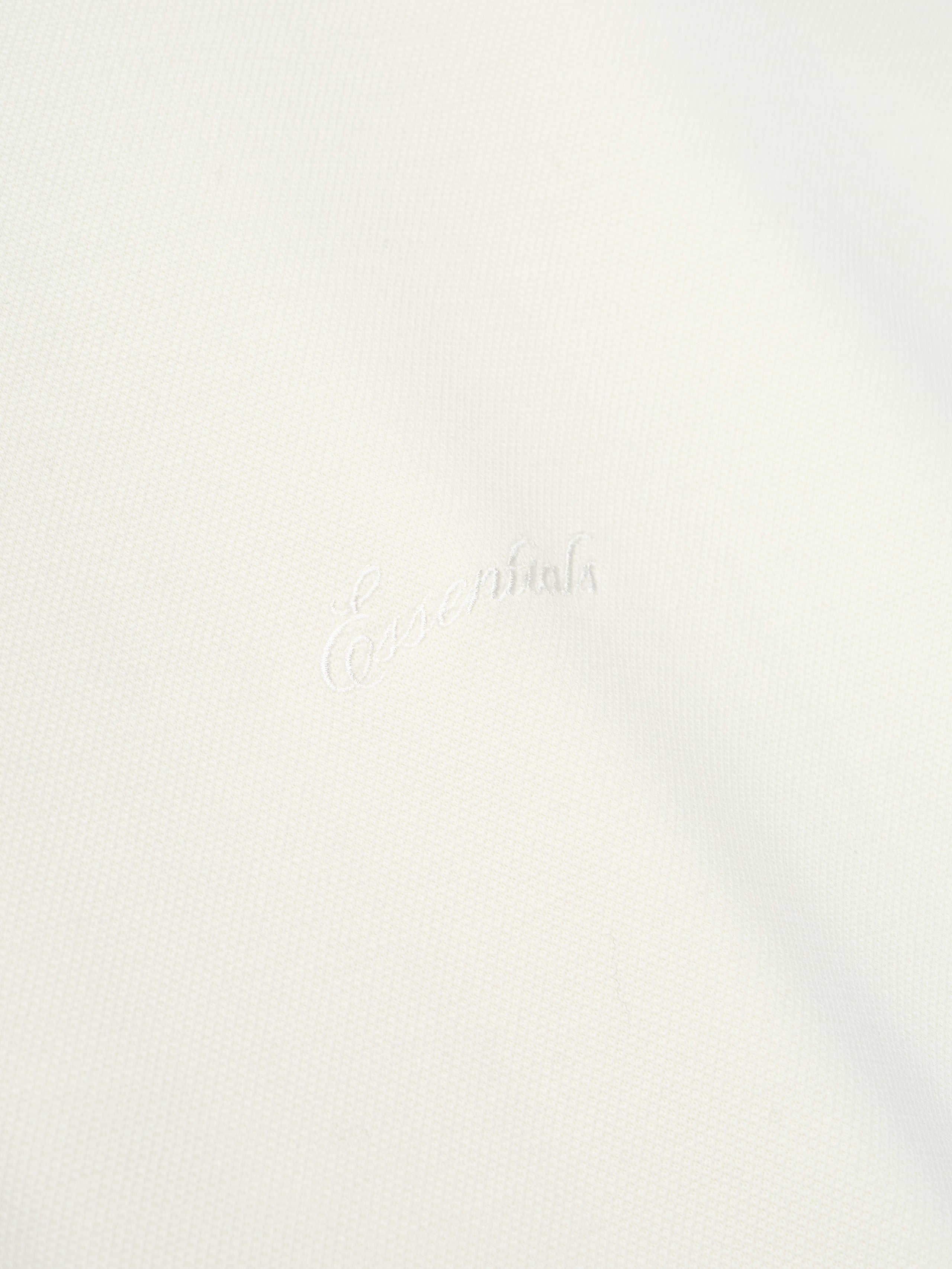 close-up of white medium-weight cotton poly pique fabric with subtle embossed Essentials signature branding