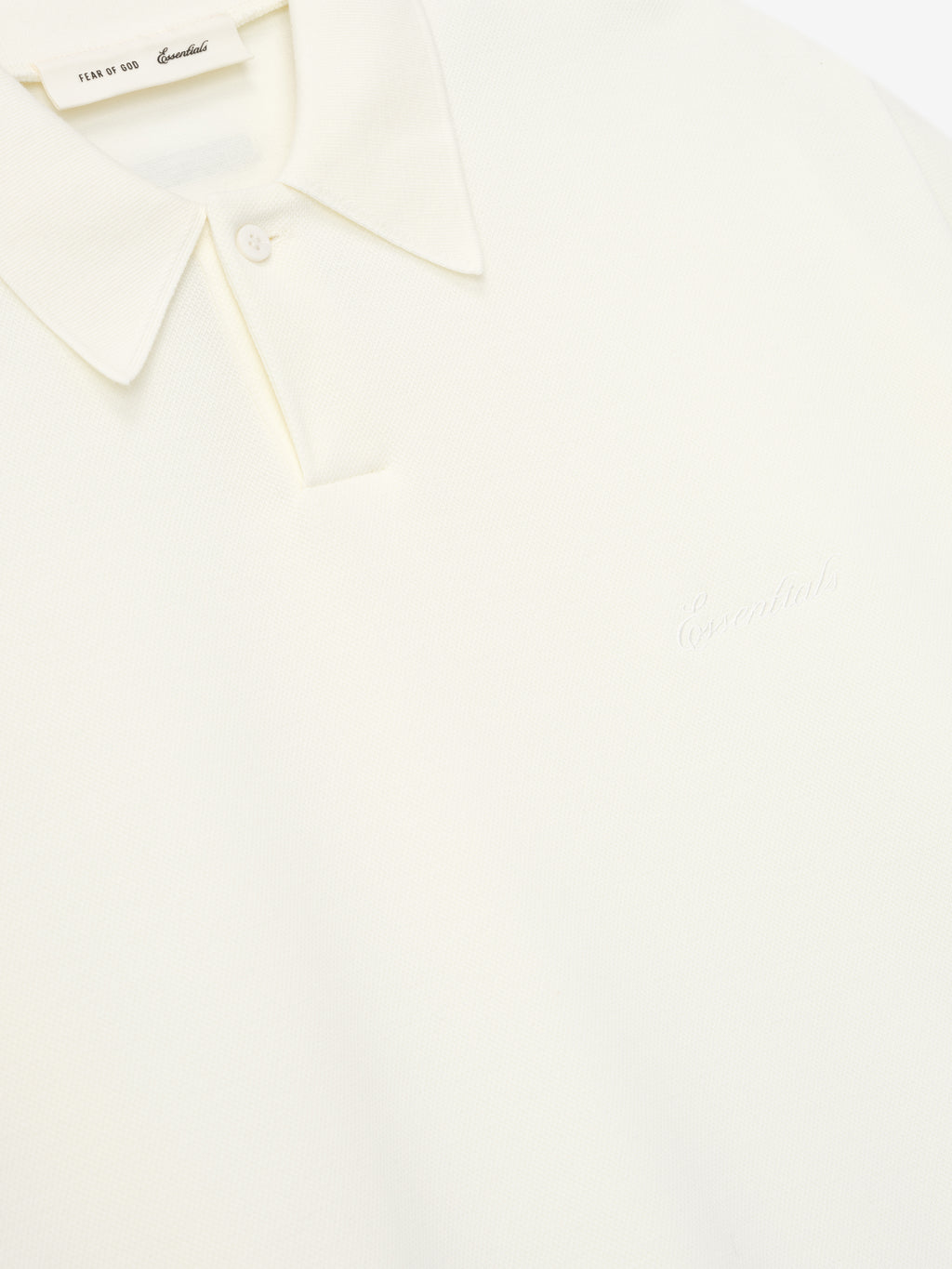 close-up of off-white medium-weight cotton poly pique polo with classic collar and subtle embossed branding on chest