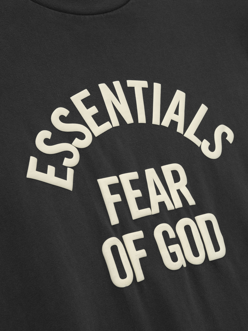 close-up of black cotton jersey tee with raised cream Essentials Fear of God print in arched layout on front
