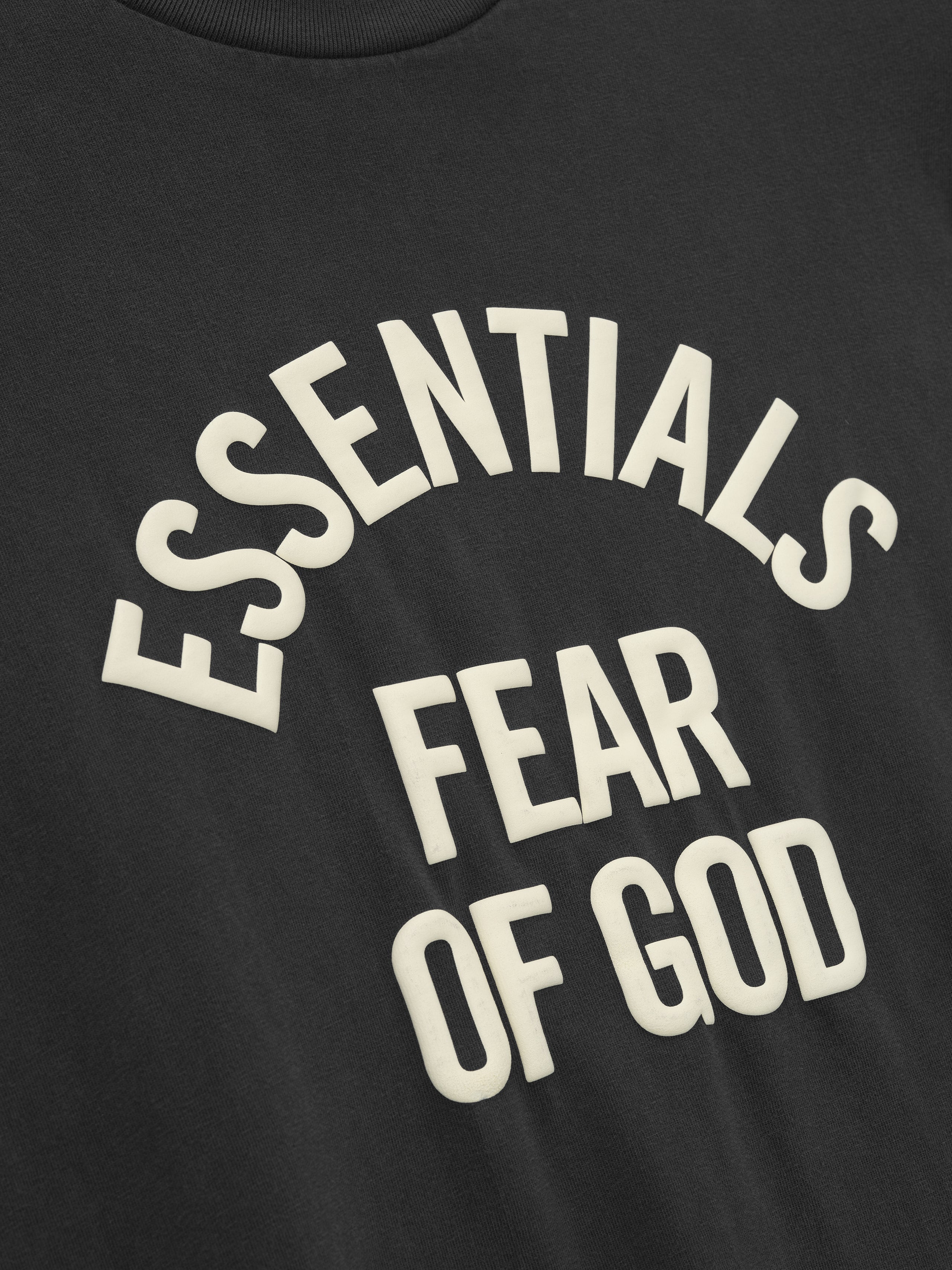 close-up of black cotton jersey tee with raised cream Essentials Fear of God print in arched layout on front