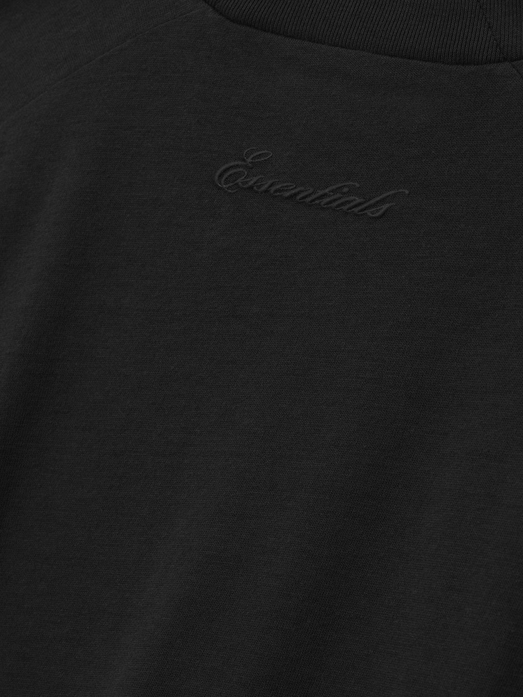 close-up of black cotton blend jersey fabric with tonal puff-print Essentials logo on women's classic long sleeve tee