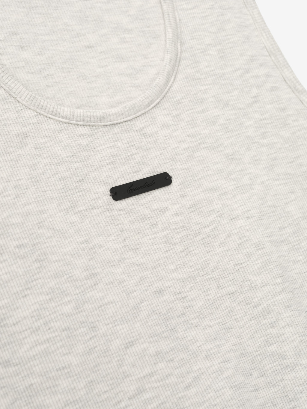 close-up of light cream ribbed cotton-rayon-spandex tank top with U-neck and small black logo patch on chest