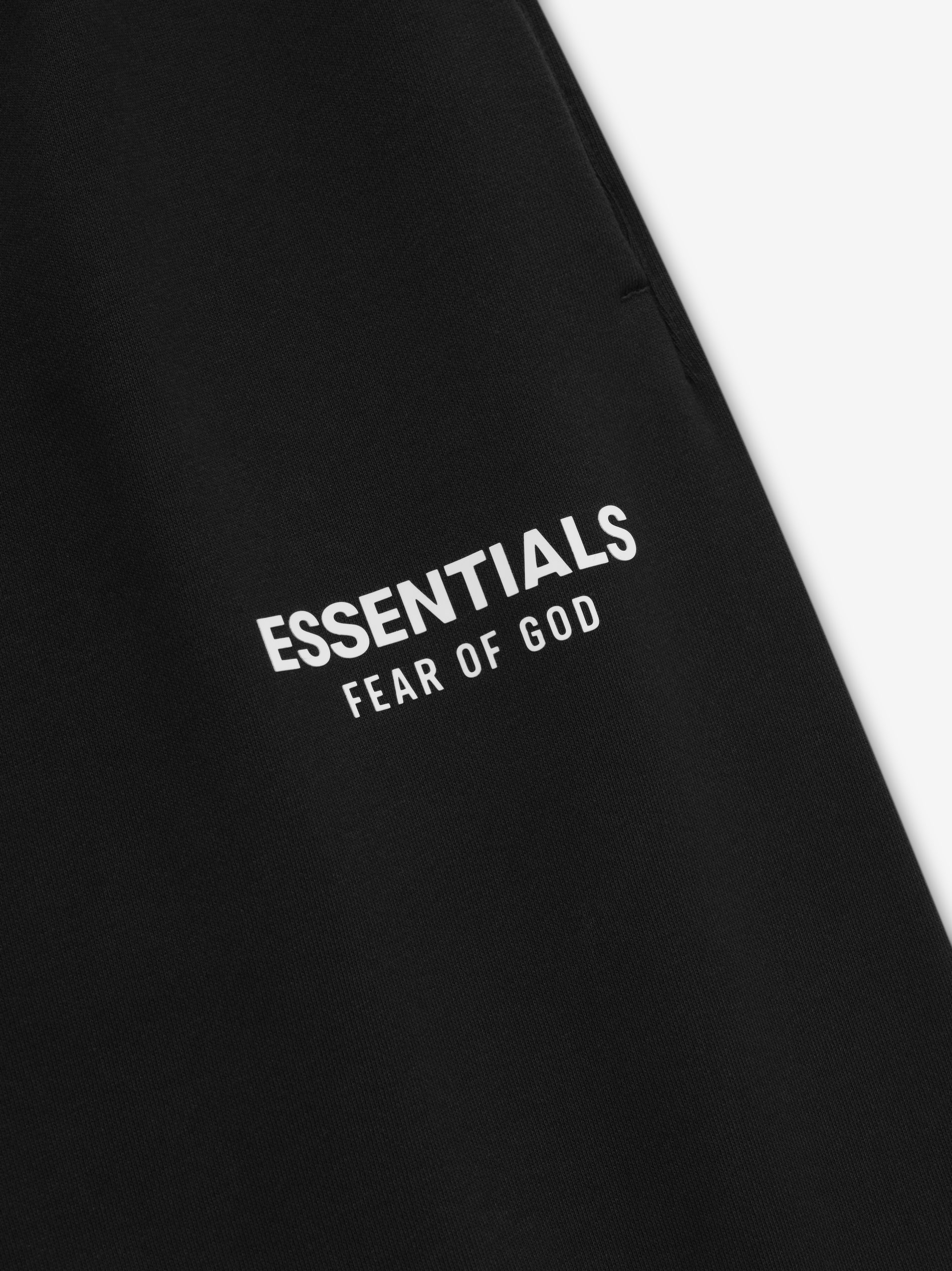 Close-up of jet black Classic Sweatpant leg with white ESSENTIALS Fear of God logo printed above pocket seam