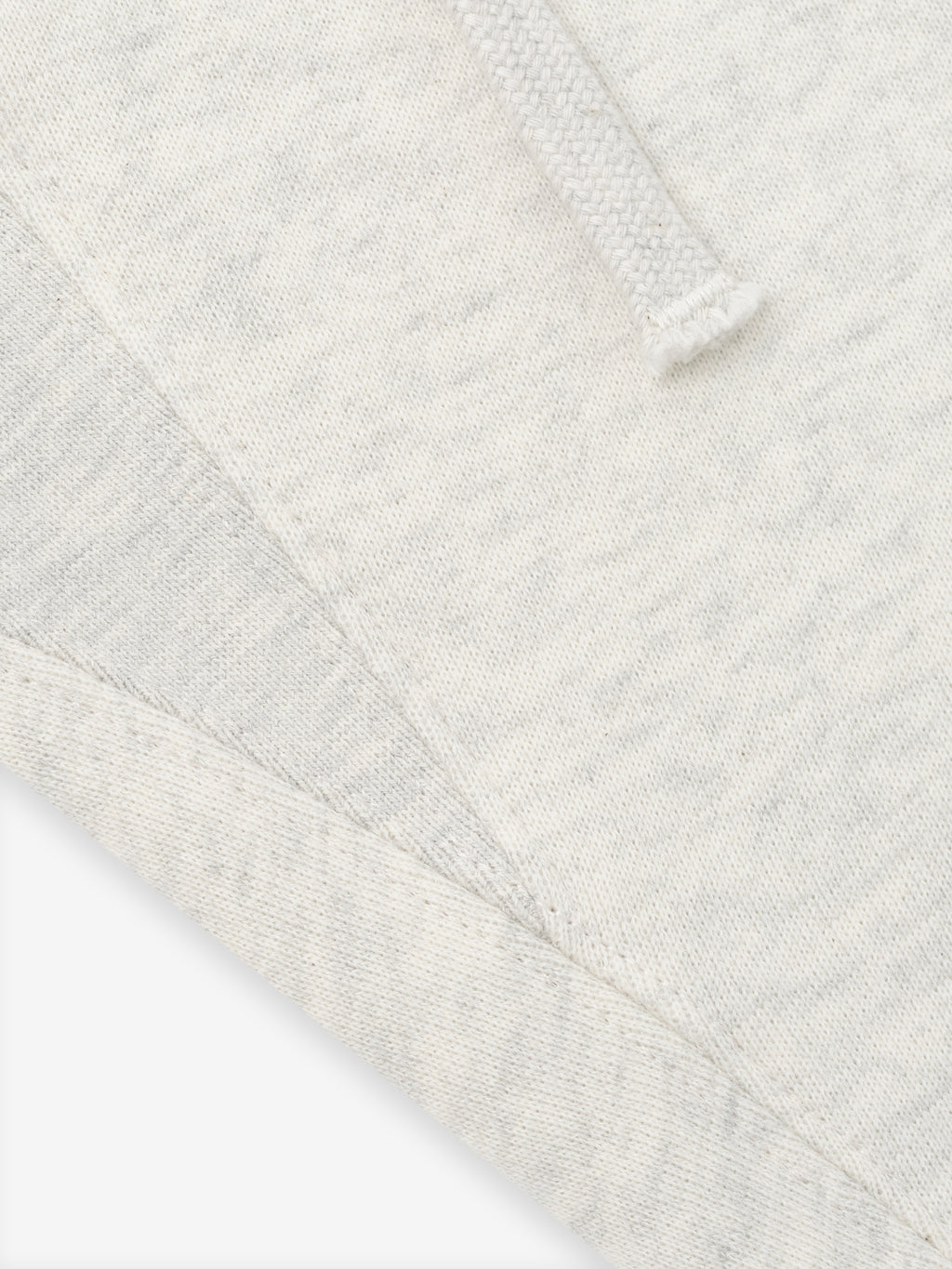 close-up of off-white fleece fabric with drawstring detail and visible seam on classic sweatpant waistband