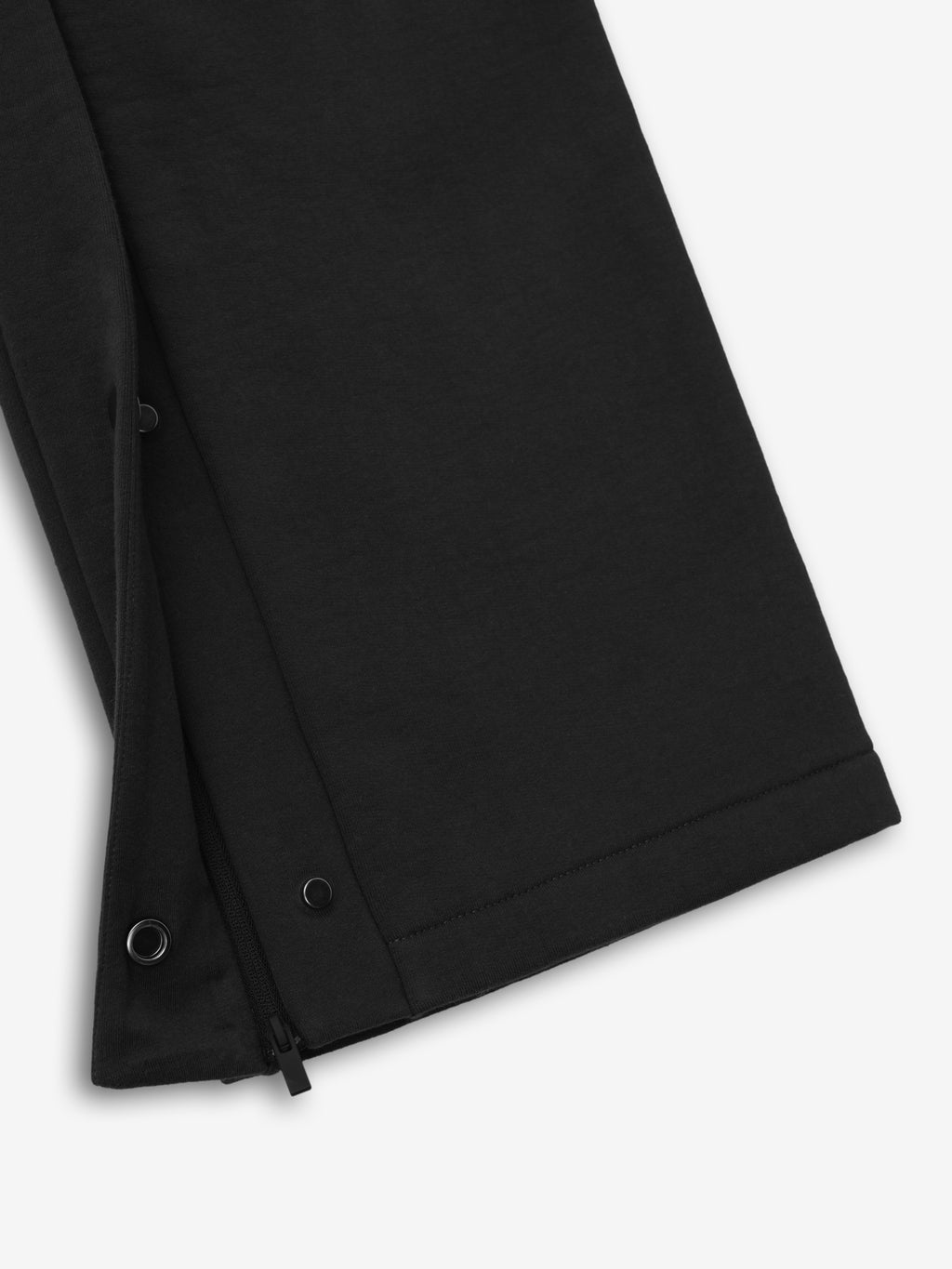 close-up of black heavyweight cotton fleece sweatpant leg with snap button tearaway side detail and zipper closure