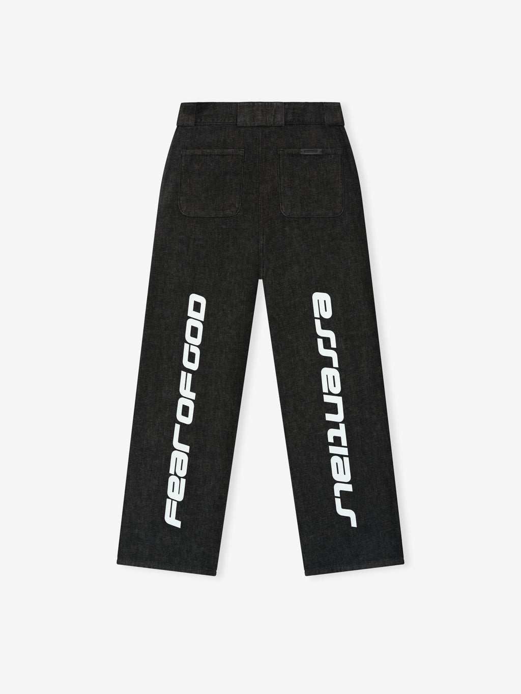 Back view of vintage black denim work pants featuring large white vertical Fear of God Essentials text on legs