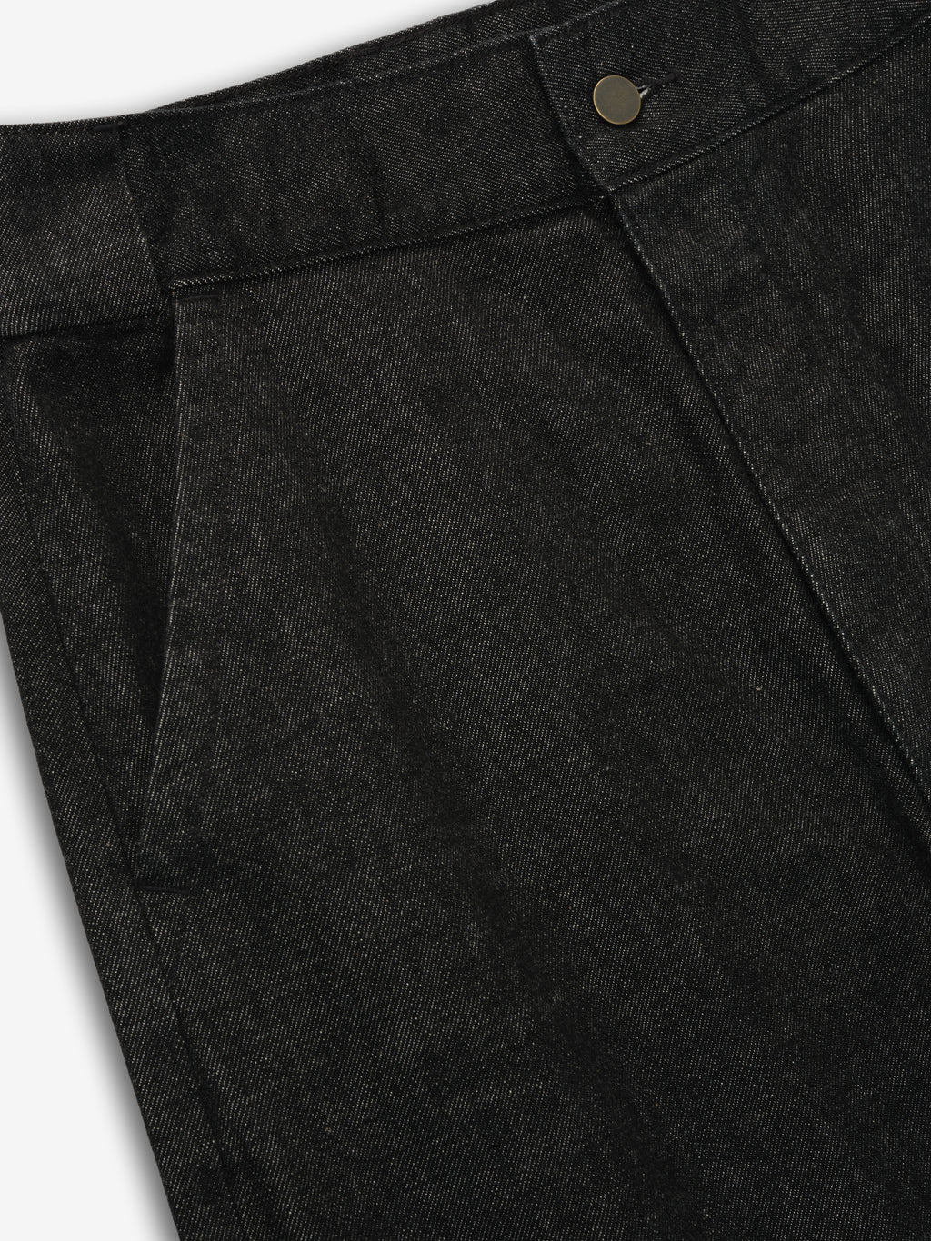 Close-up of vintage black denim work pant waistband and front pocket with button detail on gray background